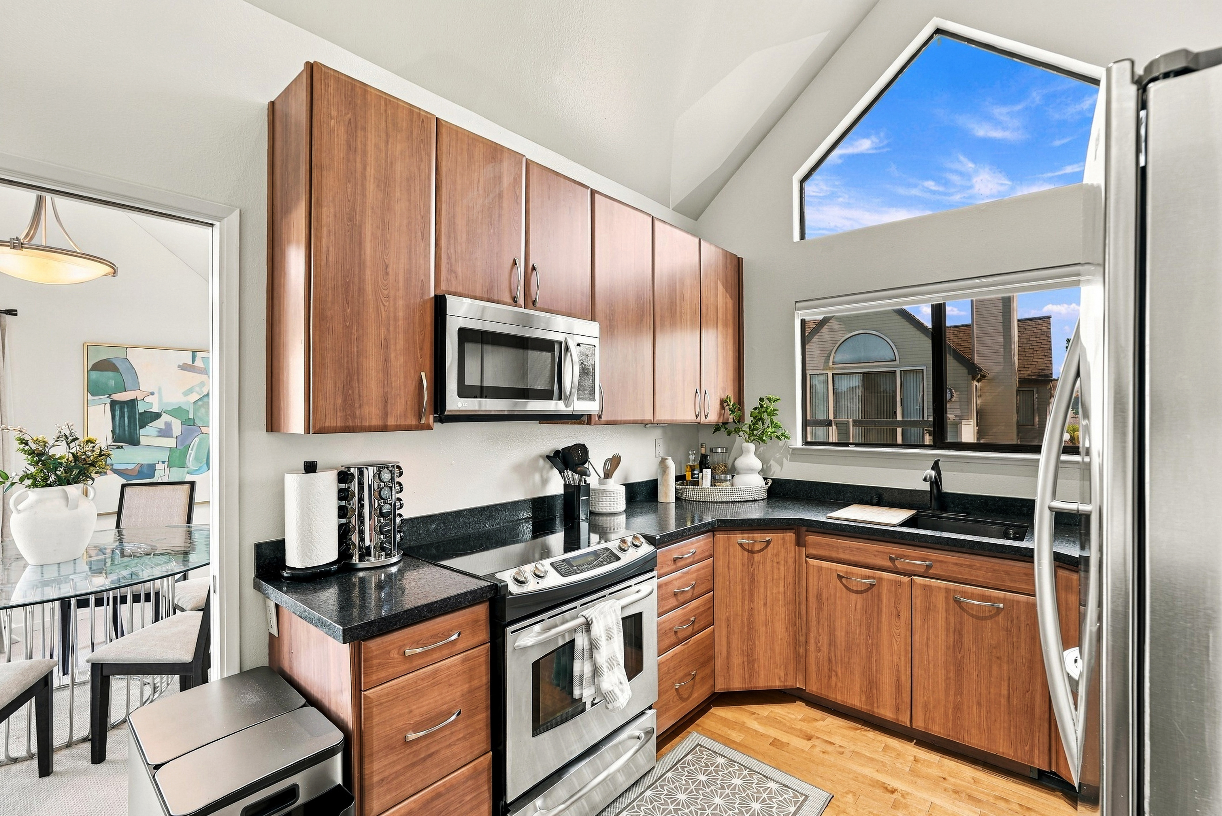 Bright vaulted kitchen with stainless steel appliances and sunny dining access