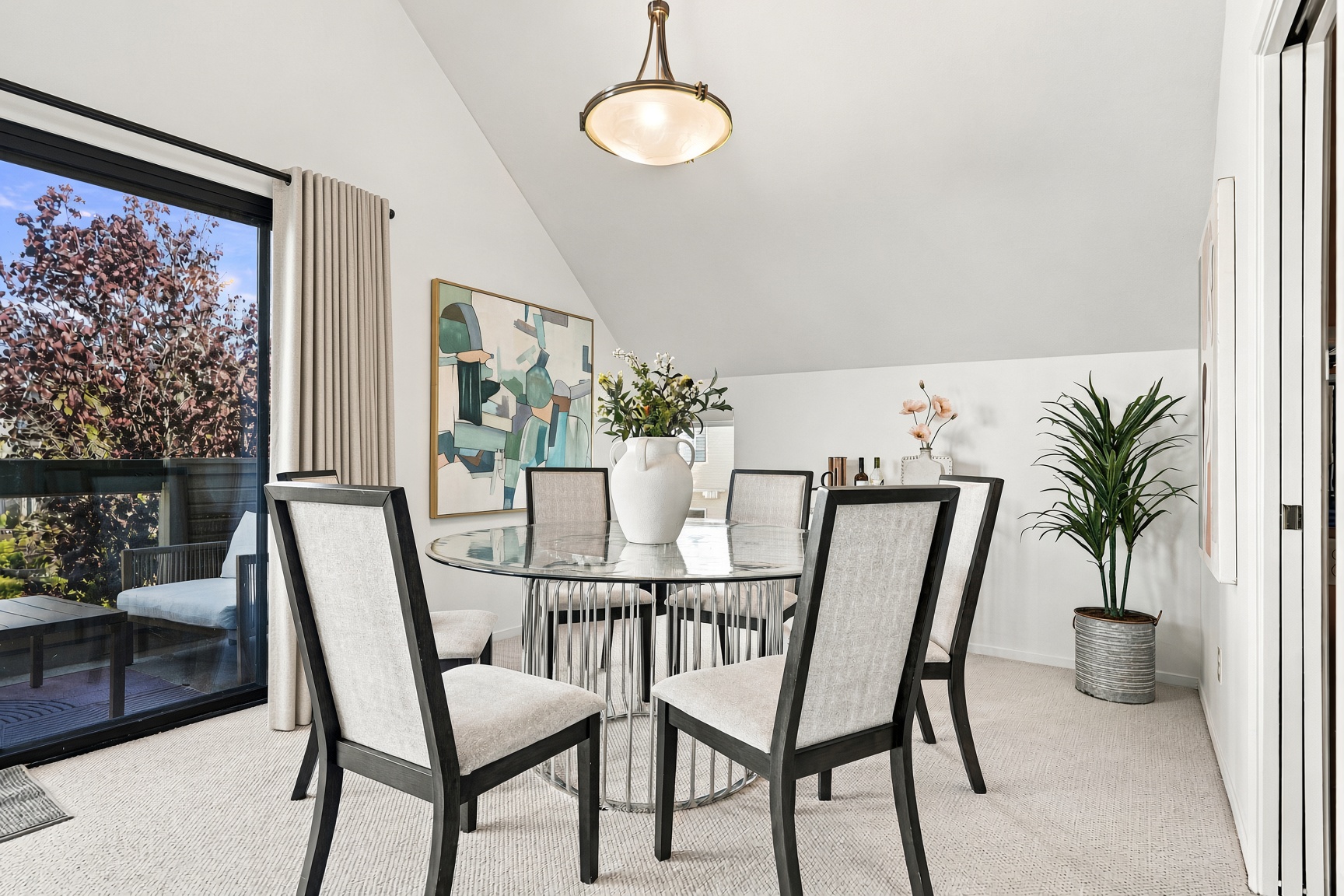 Bright vaulted dining space with glass table and access to outdoor seating