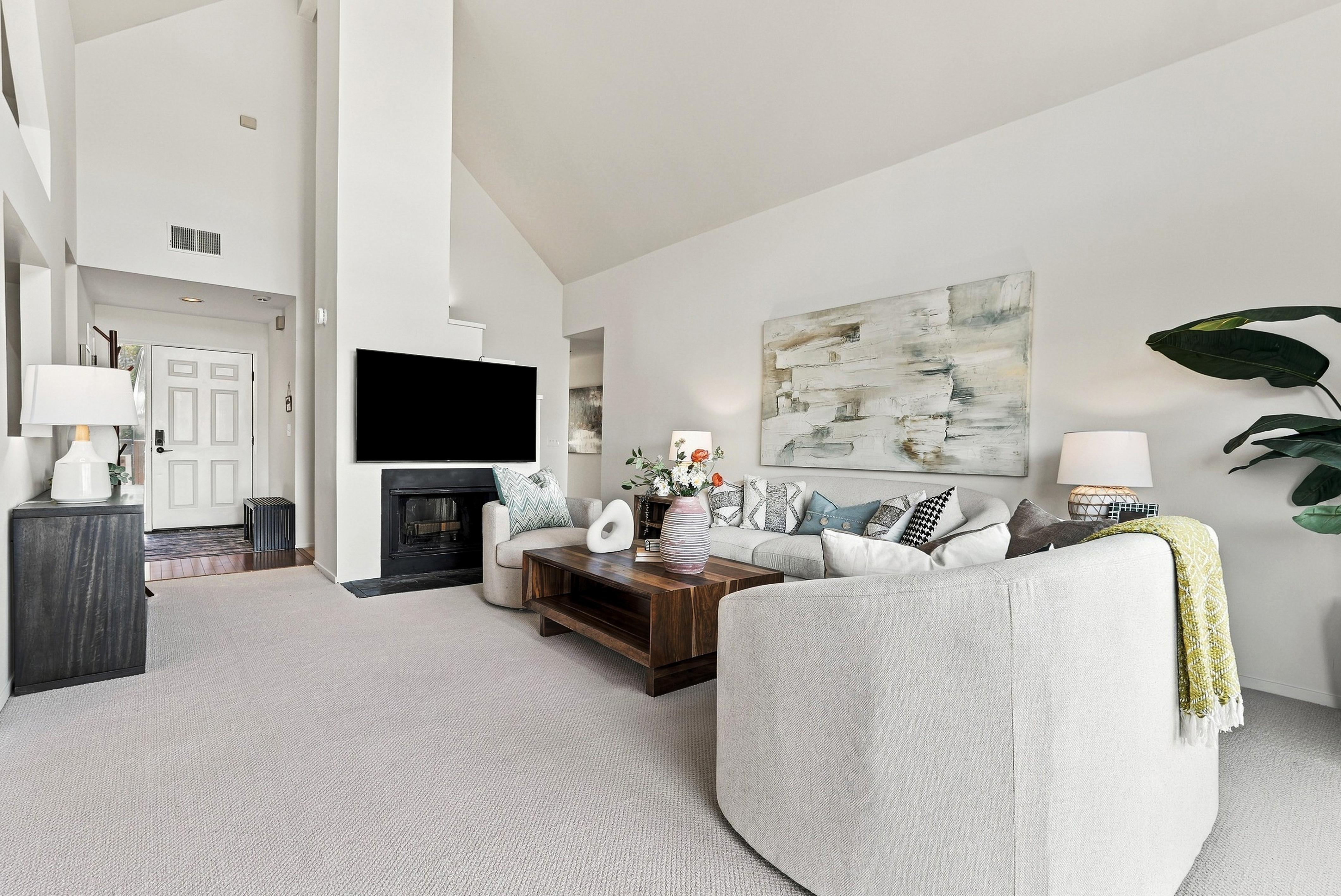Bright vaulted living room with fireplace, TV, and stylish cozy seating