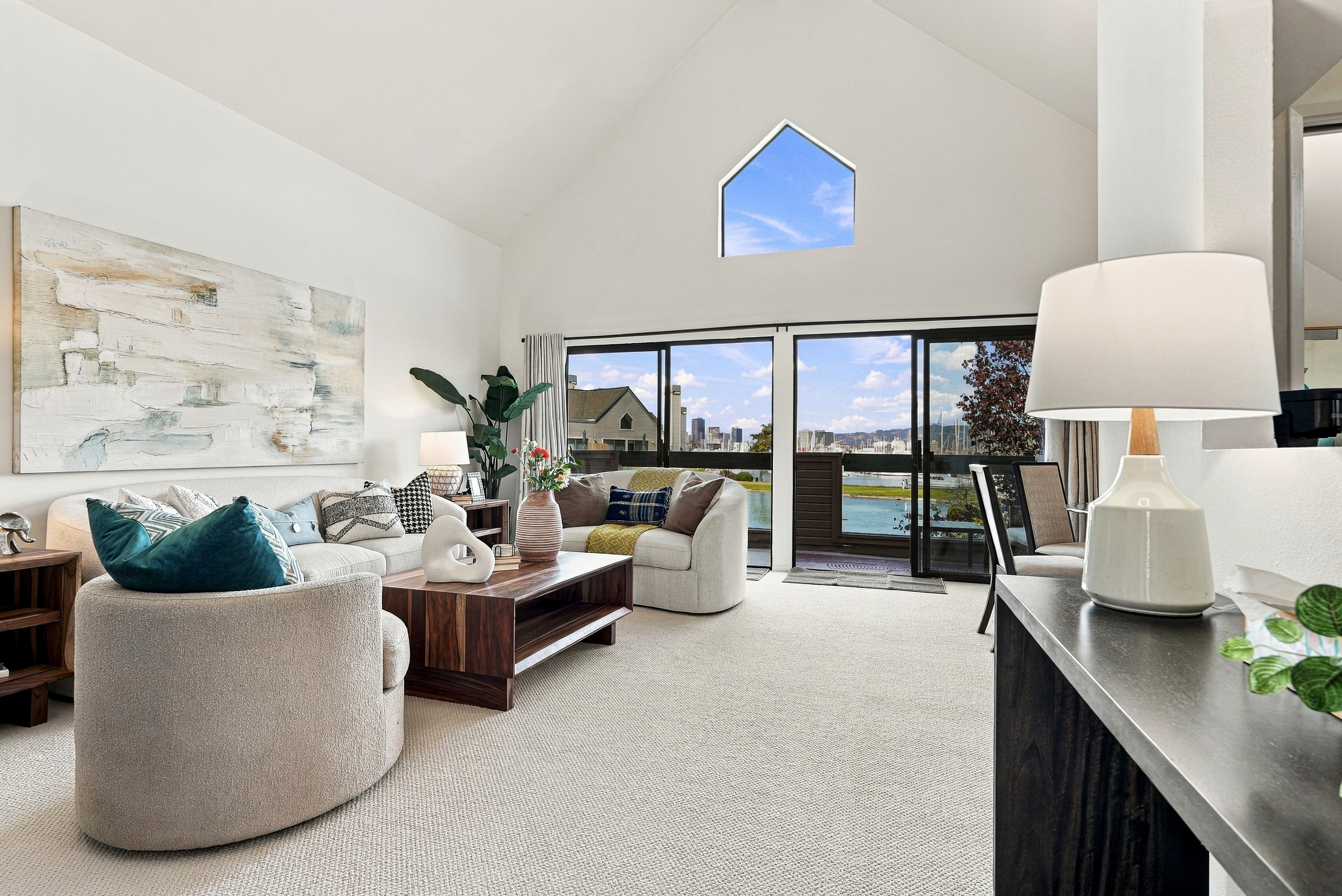 Bright vaulted living room with balcony access and city-view windows