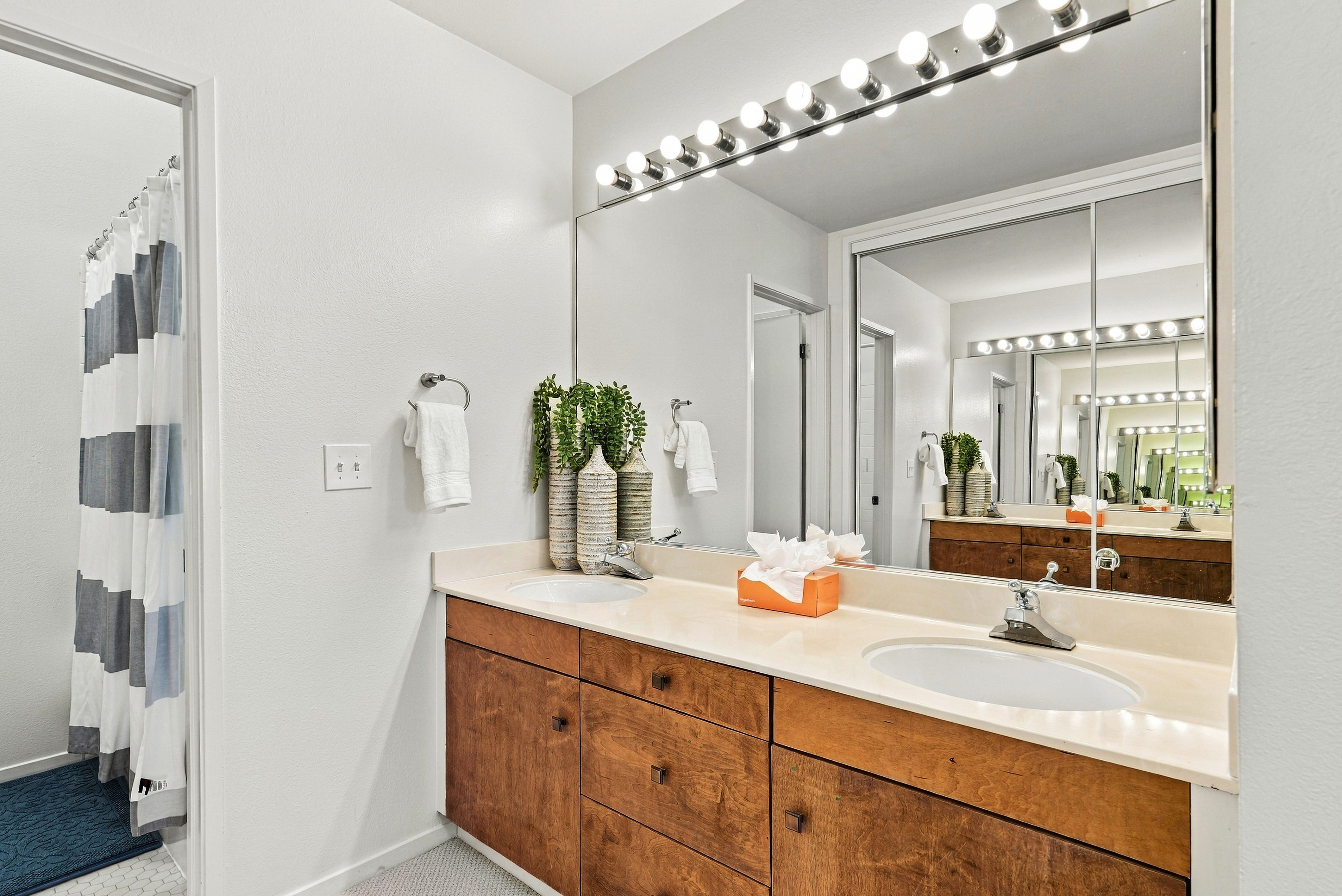 Bright bathroom vanity with oversized mirror and warm wood cabinetry