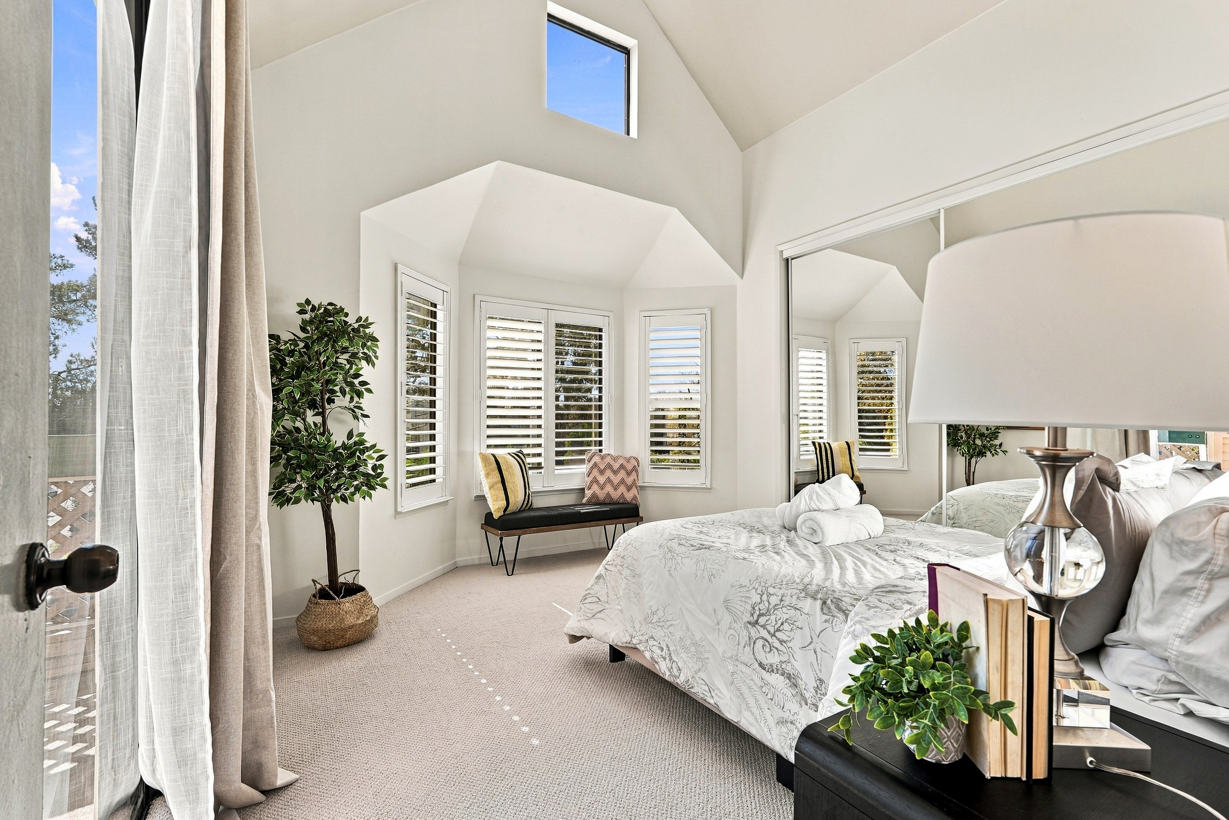 Bright vaulted bedroom with plantation shutters and elegant, airy design