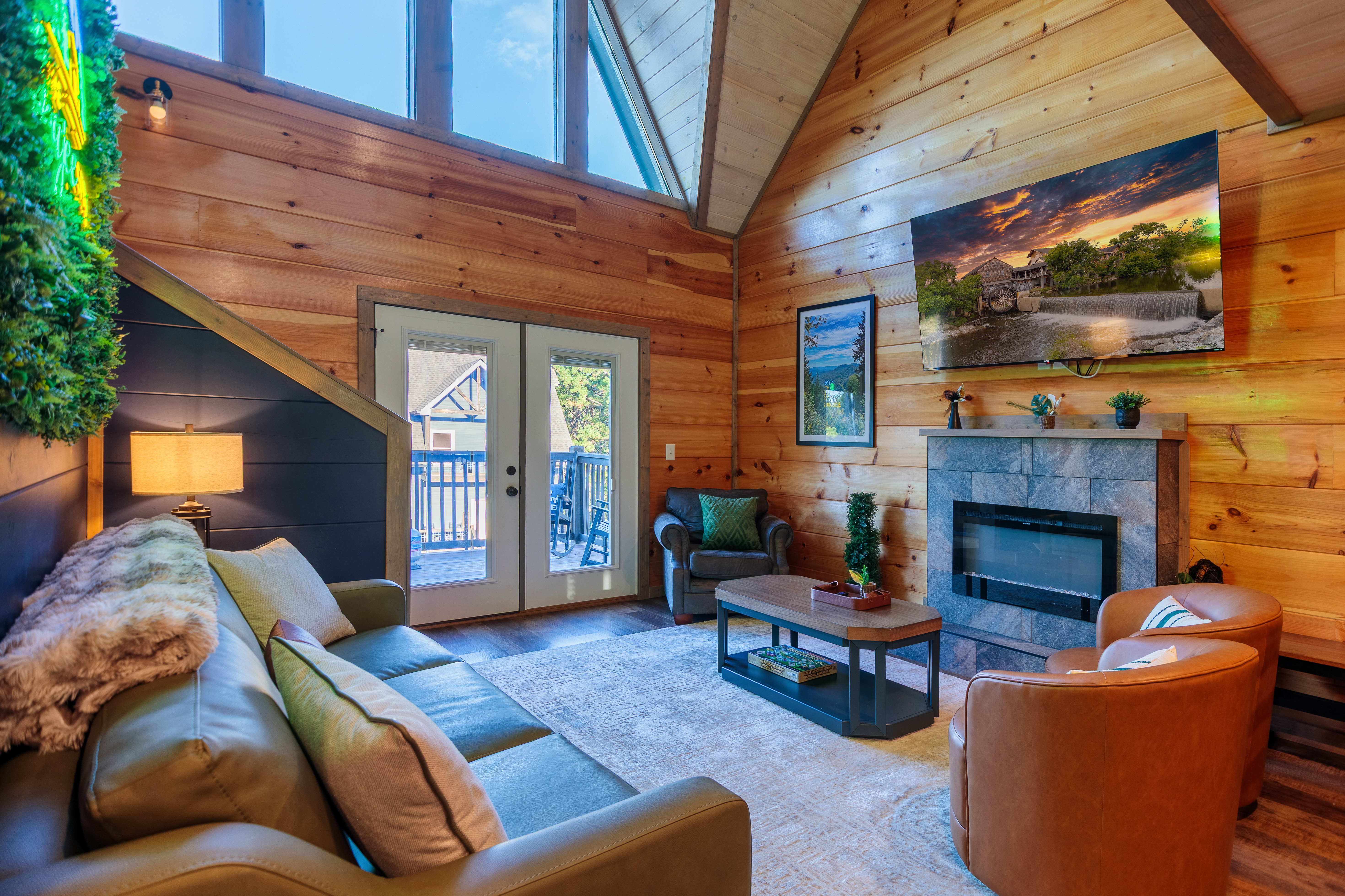 Cozy cabin living room with vaulted ceilings, fireplace, and deck access