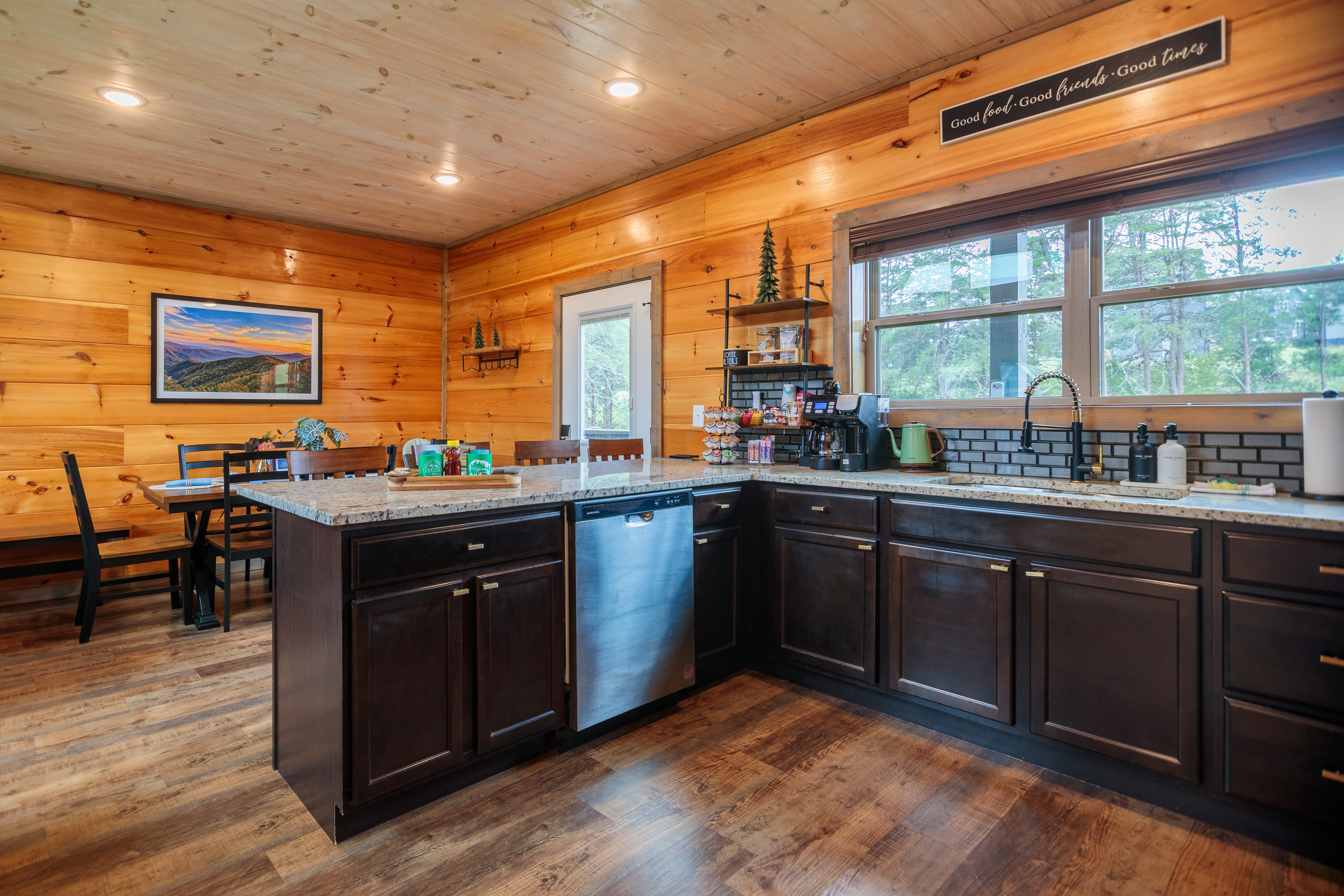 Rustic modern kitchen with island, dining space, and serene wooded views