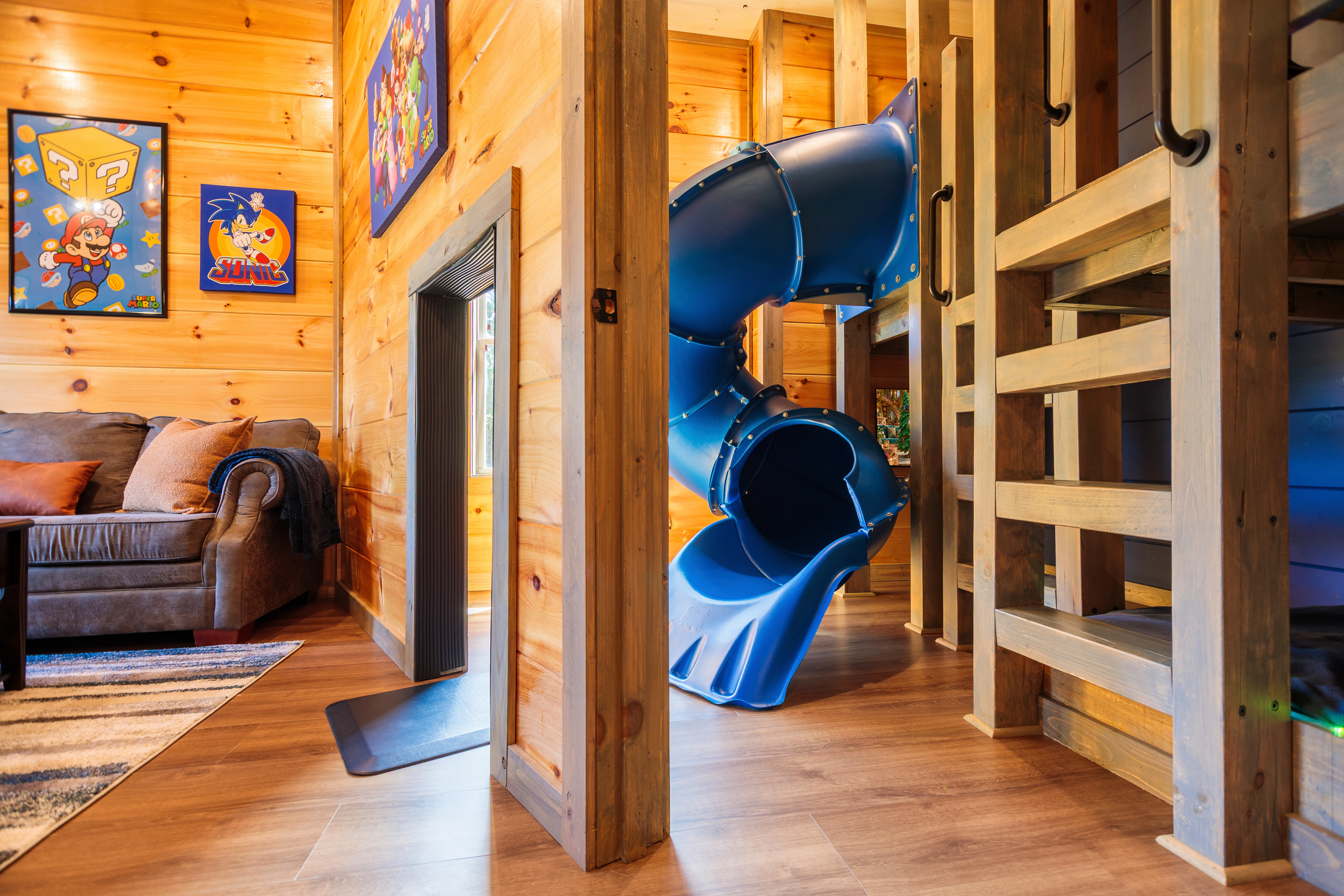 Playful cabin interior with loft ladder, cozy lounge, and built-in slide