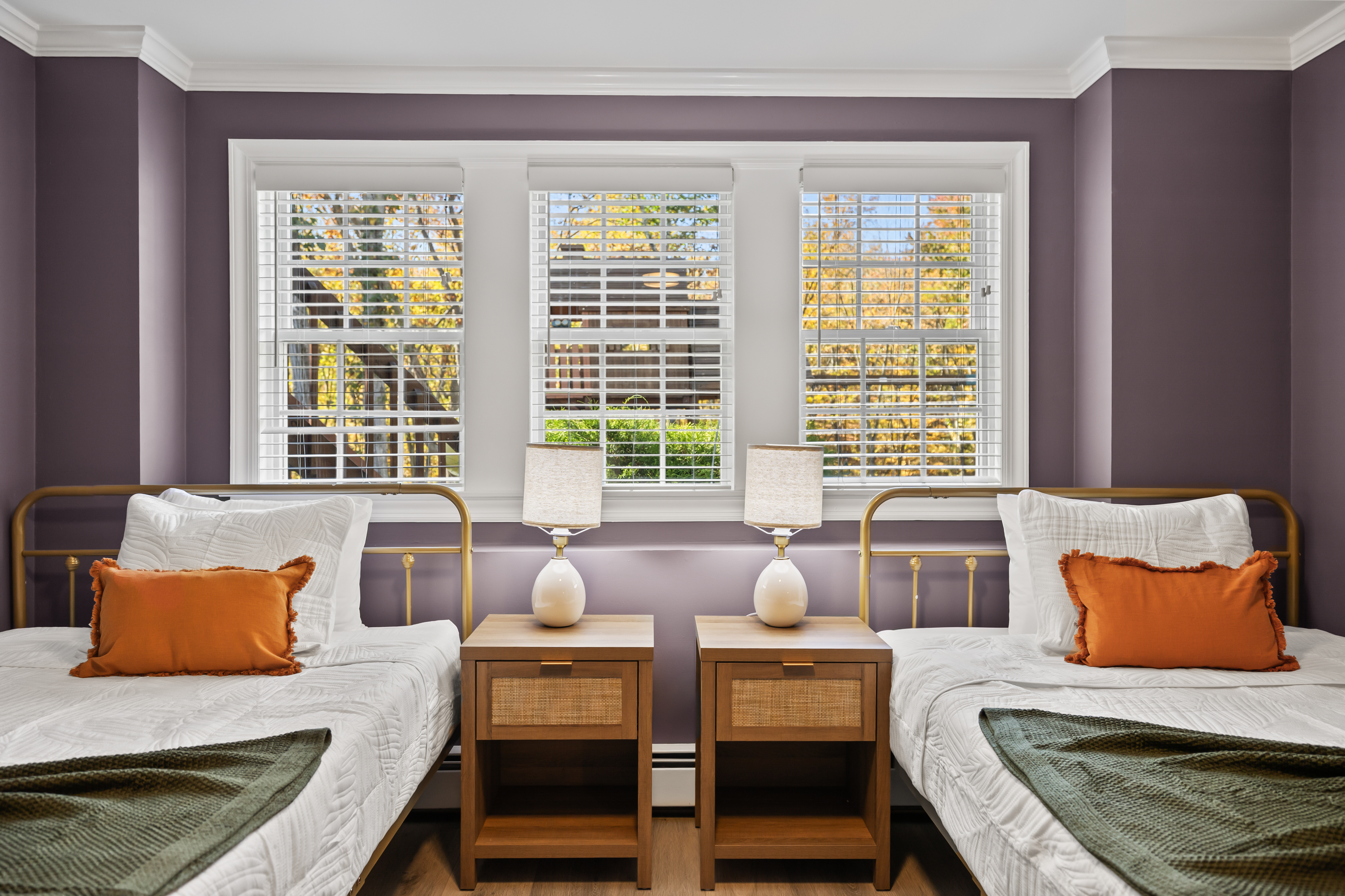 Bright twin bedroom with bay windows, stylish accents, and cozy shared layout