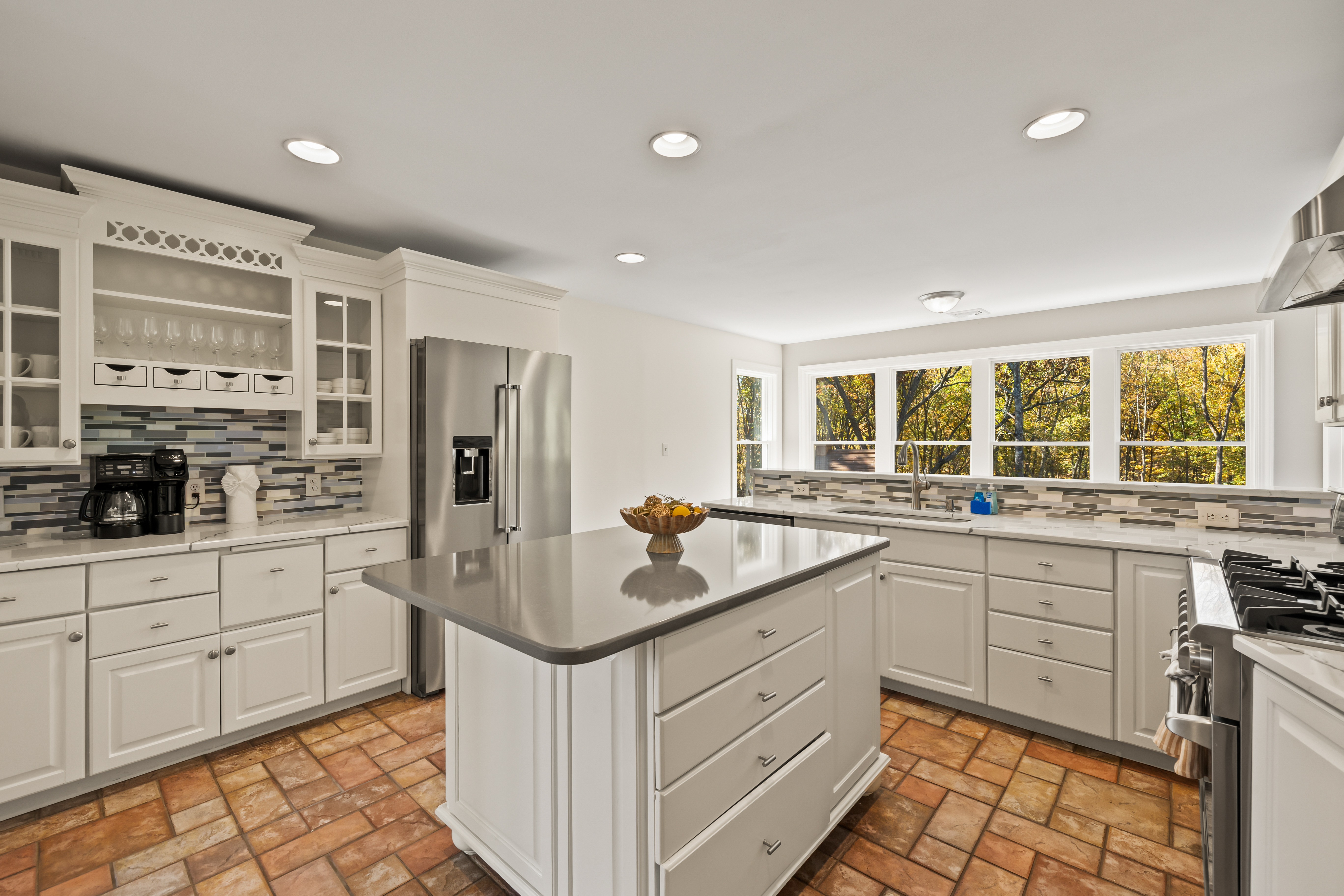 Bright gourmet kitchen with large island, gas range, and scenic window views