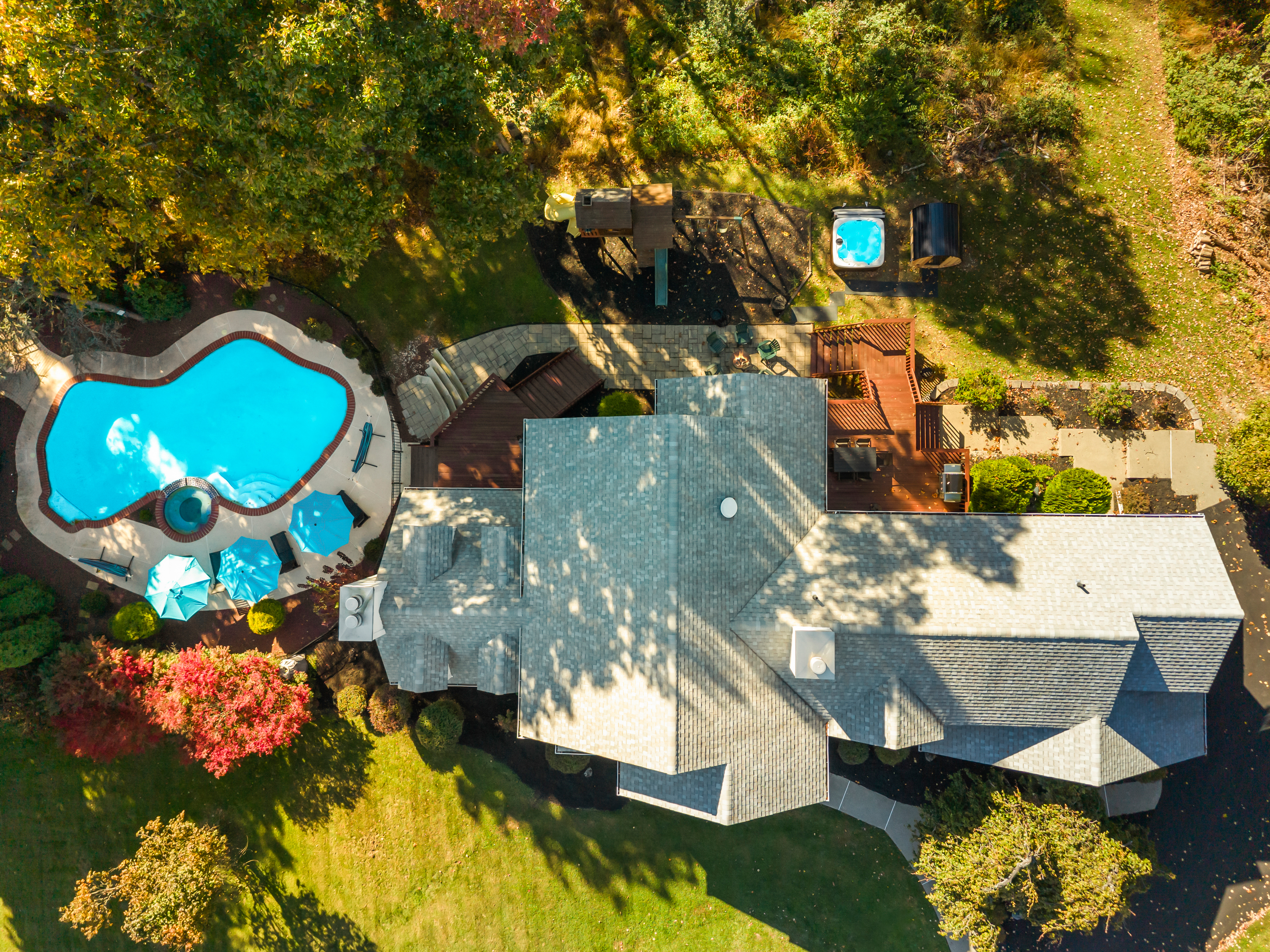 Aerial view of home with private pool, hot tub, and spacious outdoor decks