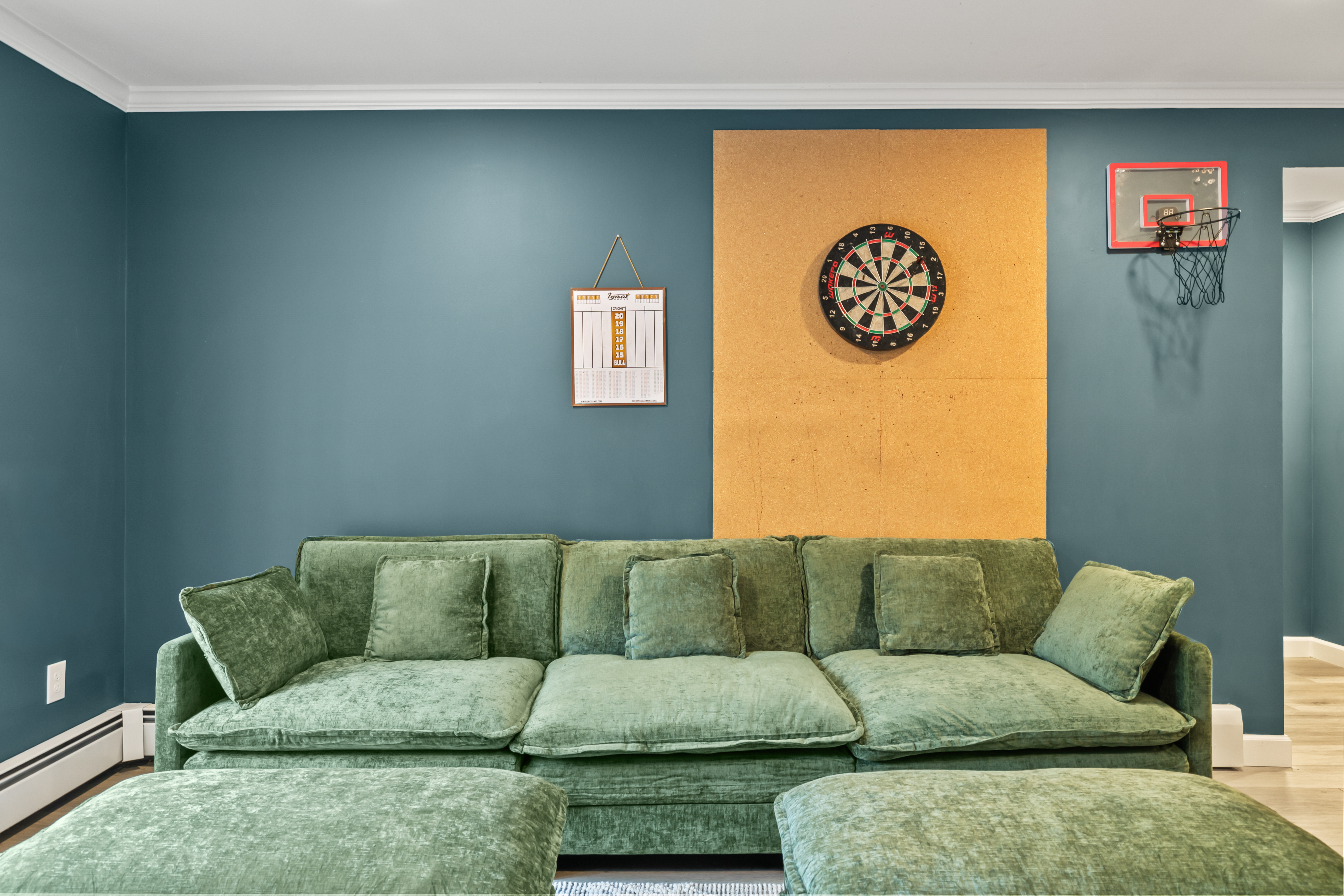 Cozy game lounge with plush sectional, dartboard, and mini hoop