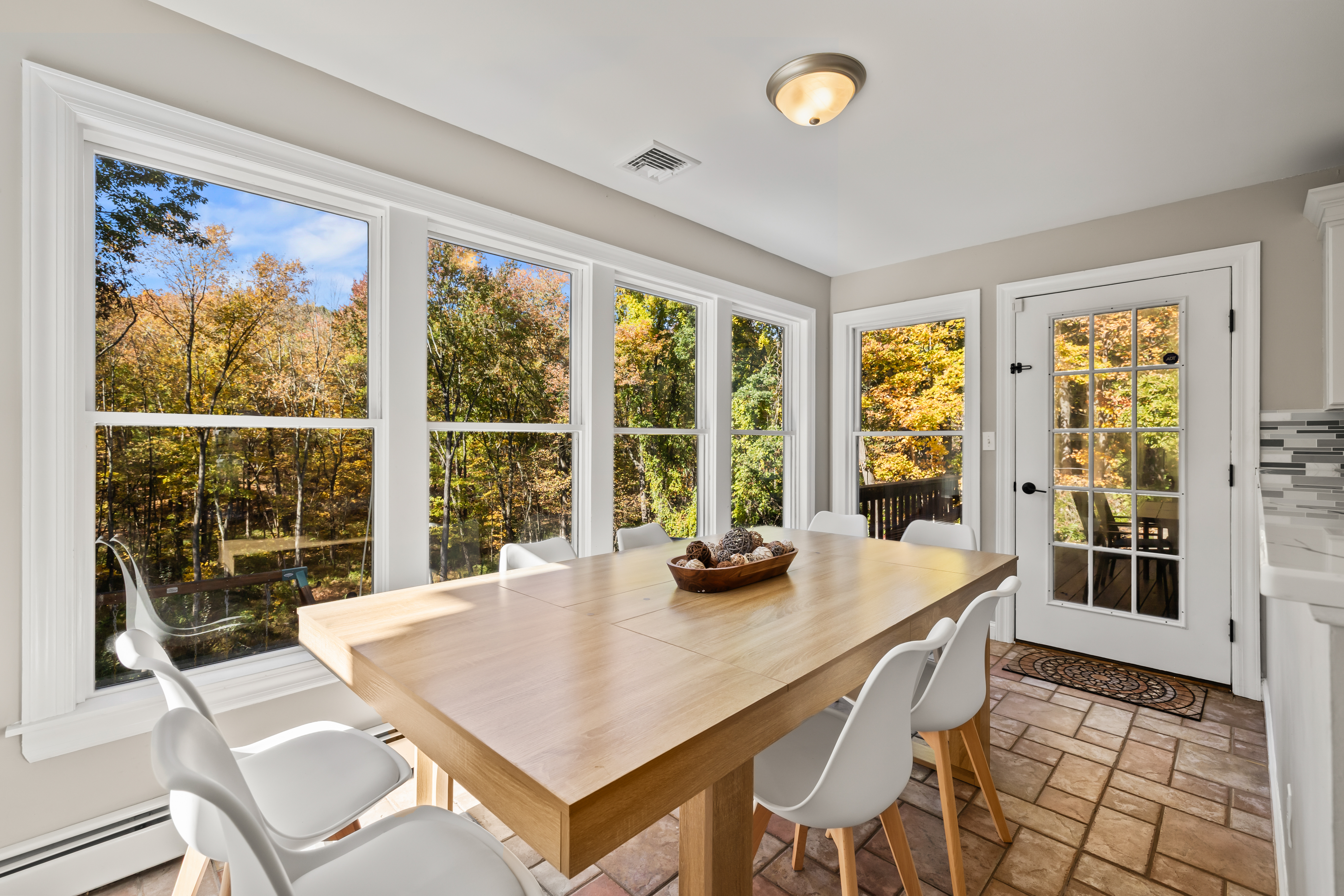 Sun-filled dining space with wooded views and deck access