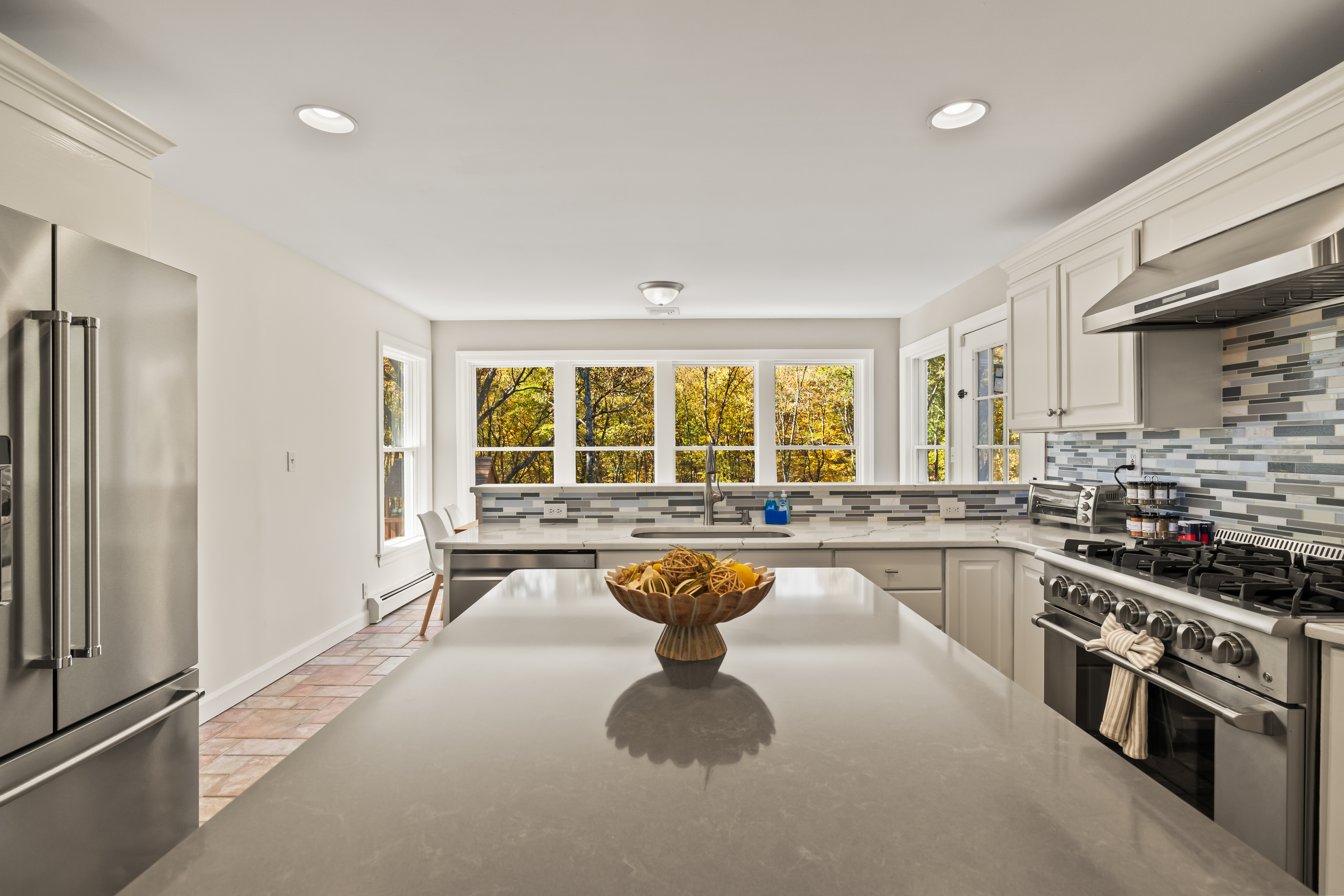 Bright modern kitchen with large island, stainless appliances, and leafy views