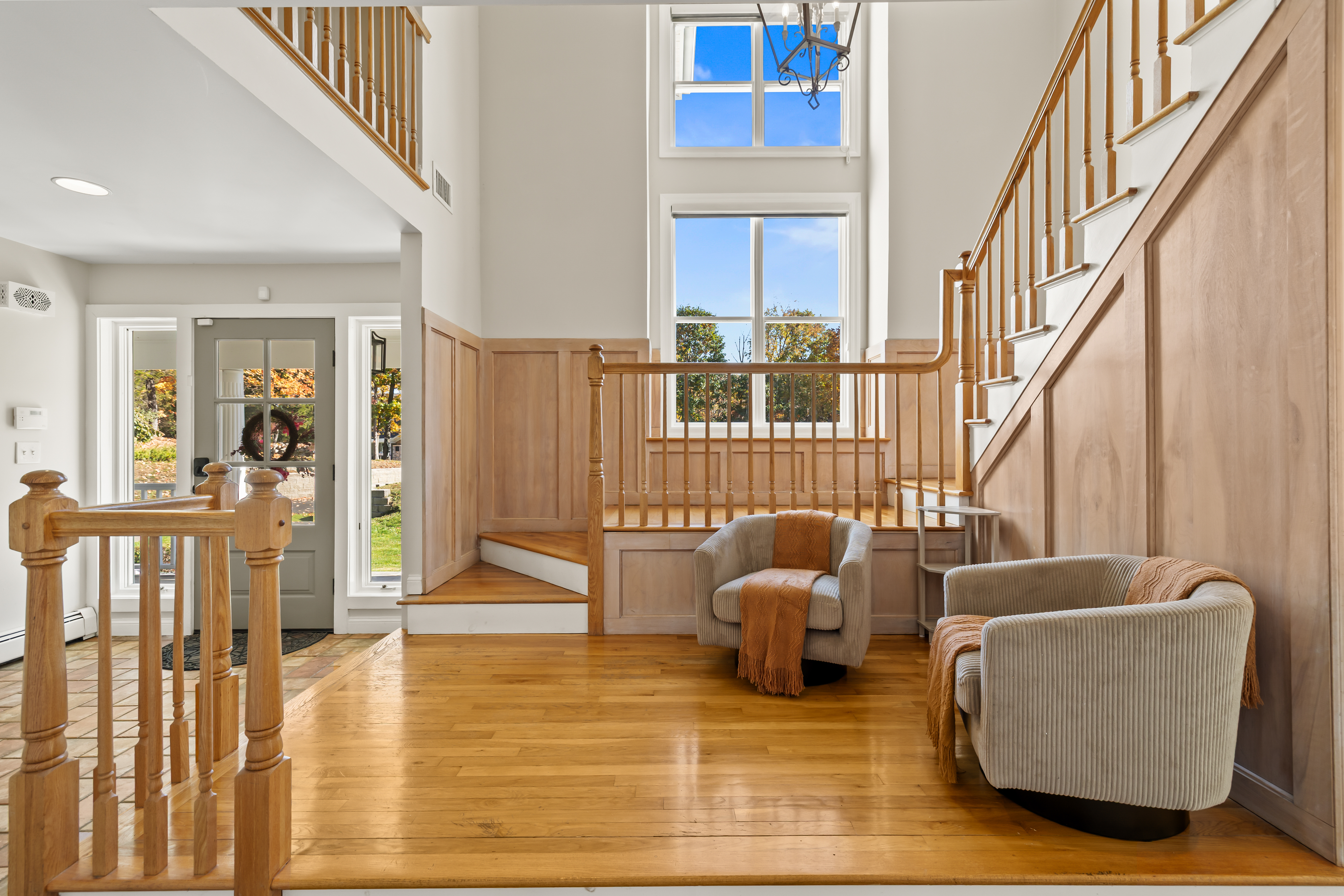 Bright two-story foyer with elegant staircase and cozy seating area