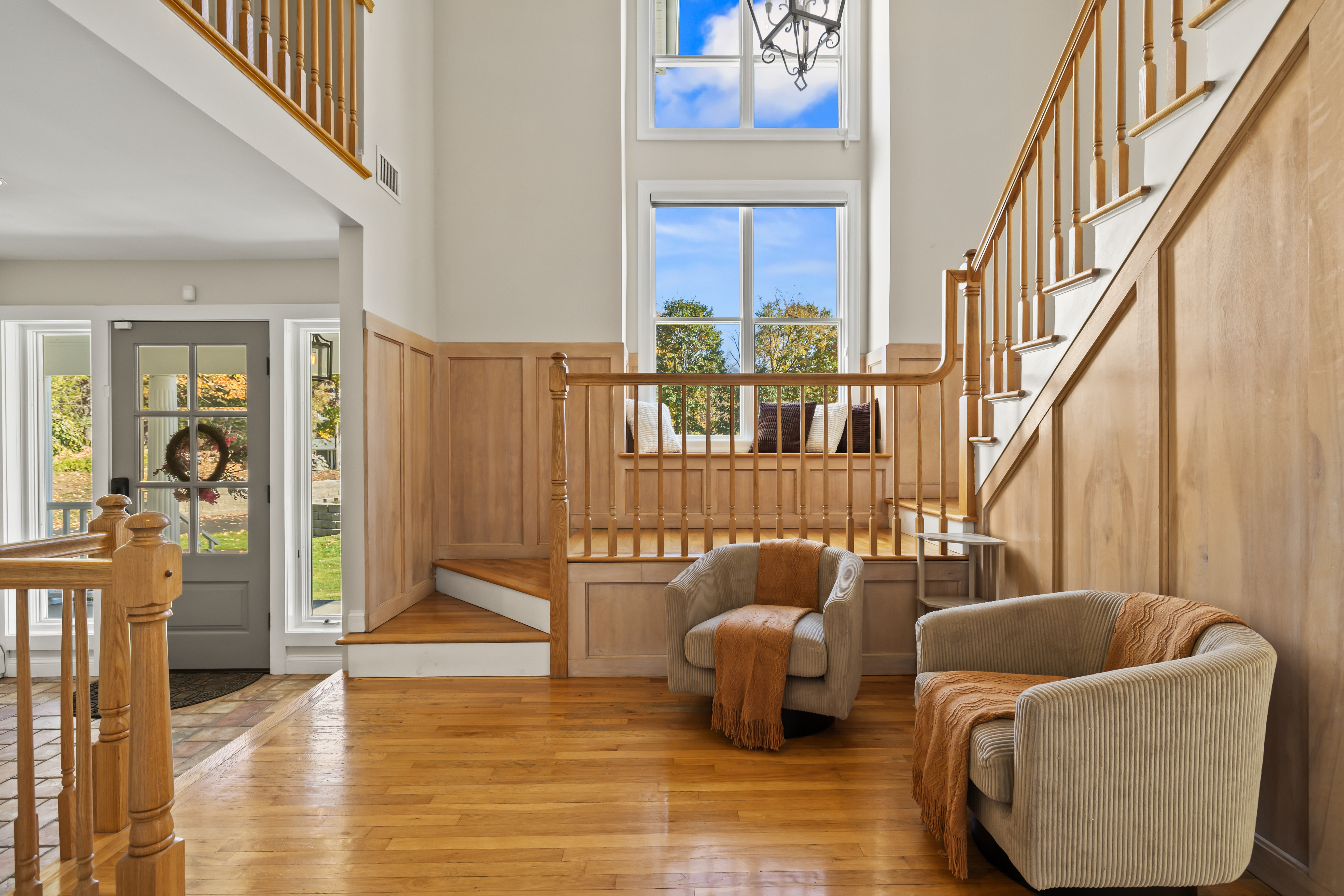 Grand sunlit foyer with soaring ceilings and a cozy sitting nook