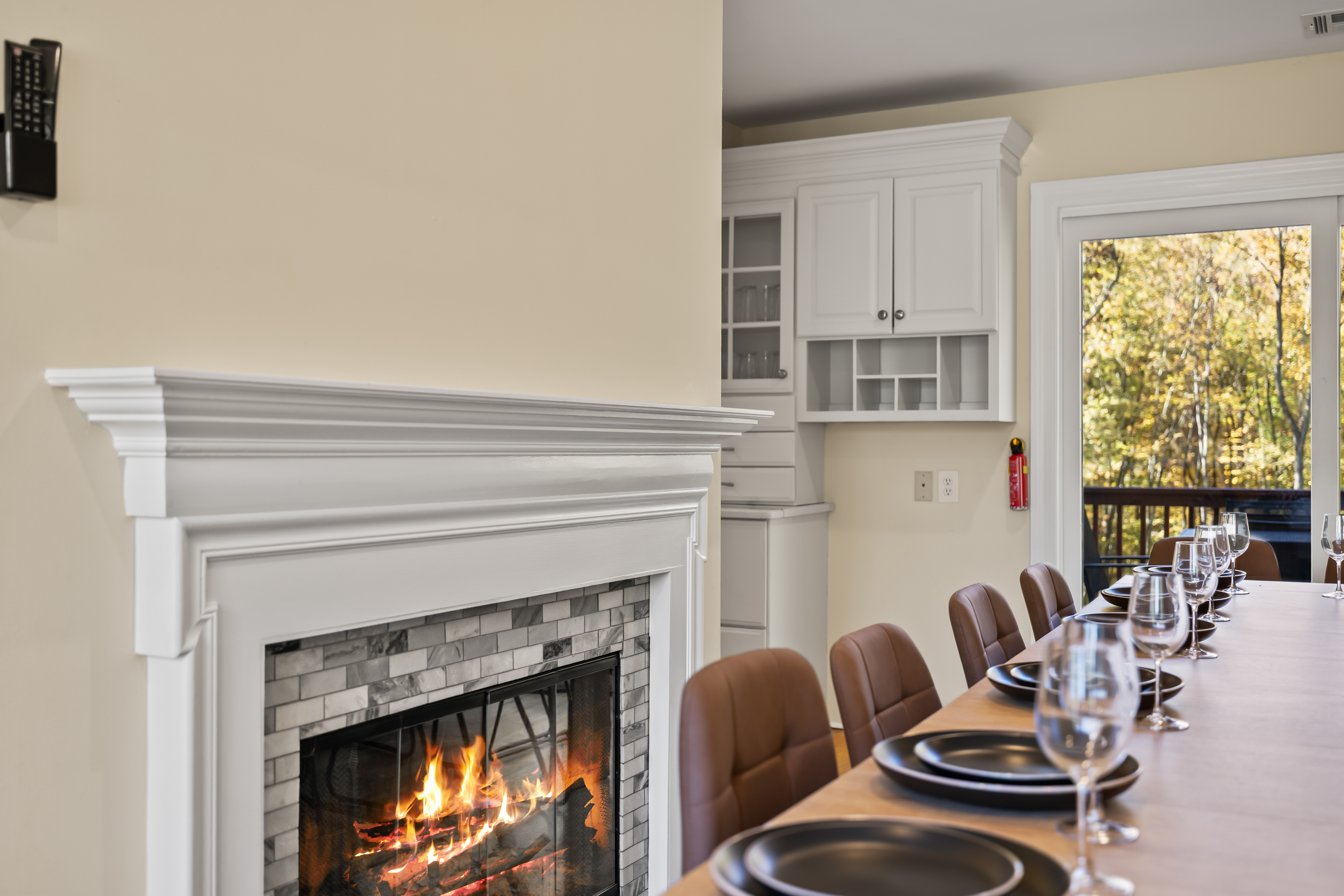 Cozy fireplace dining room with elegant table setting and wooded views