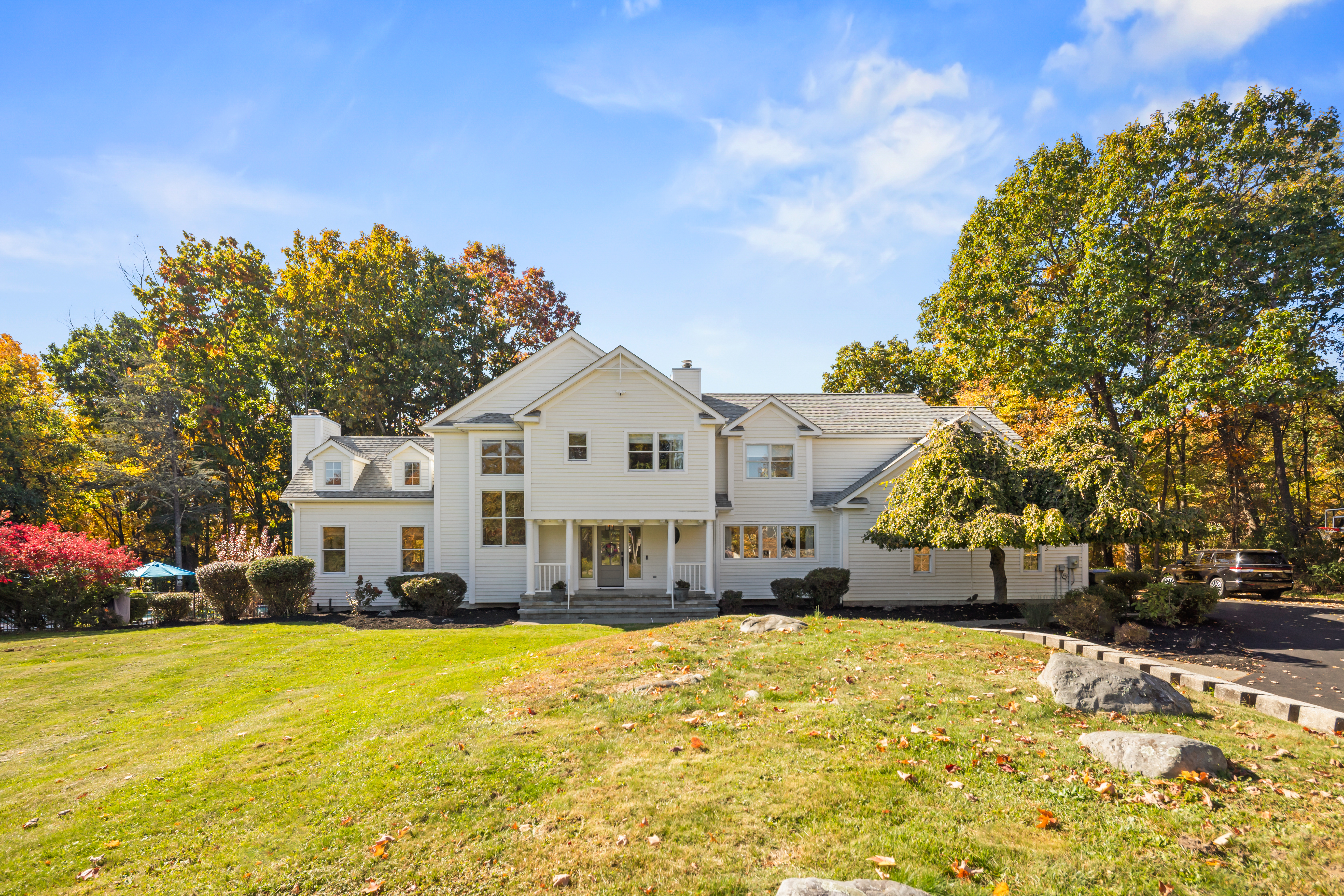 Grand white estate with expansive lawn and serene wooded setting