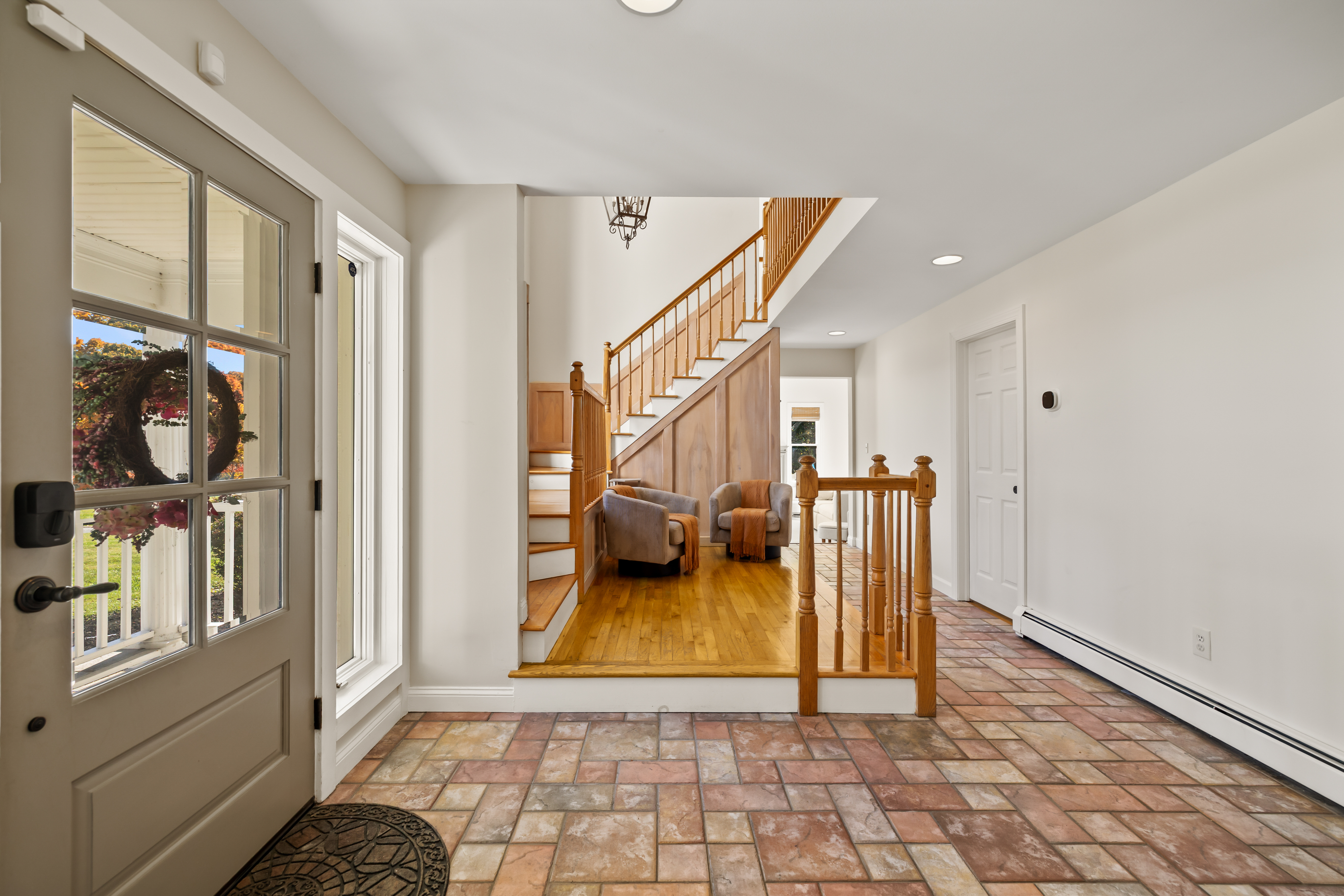 Bright, welcoming entryway with classic wood staircase and airy natural light