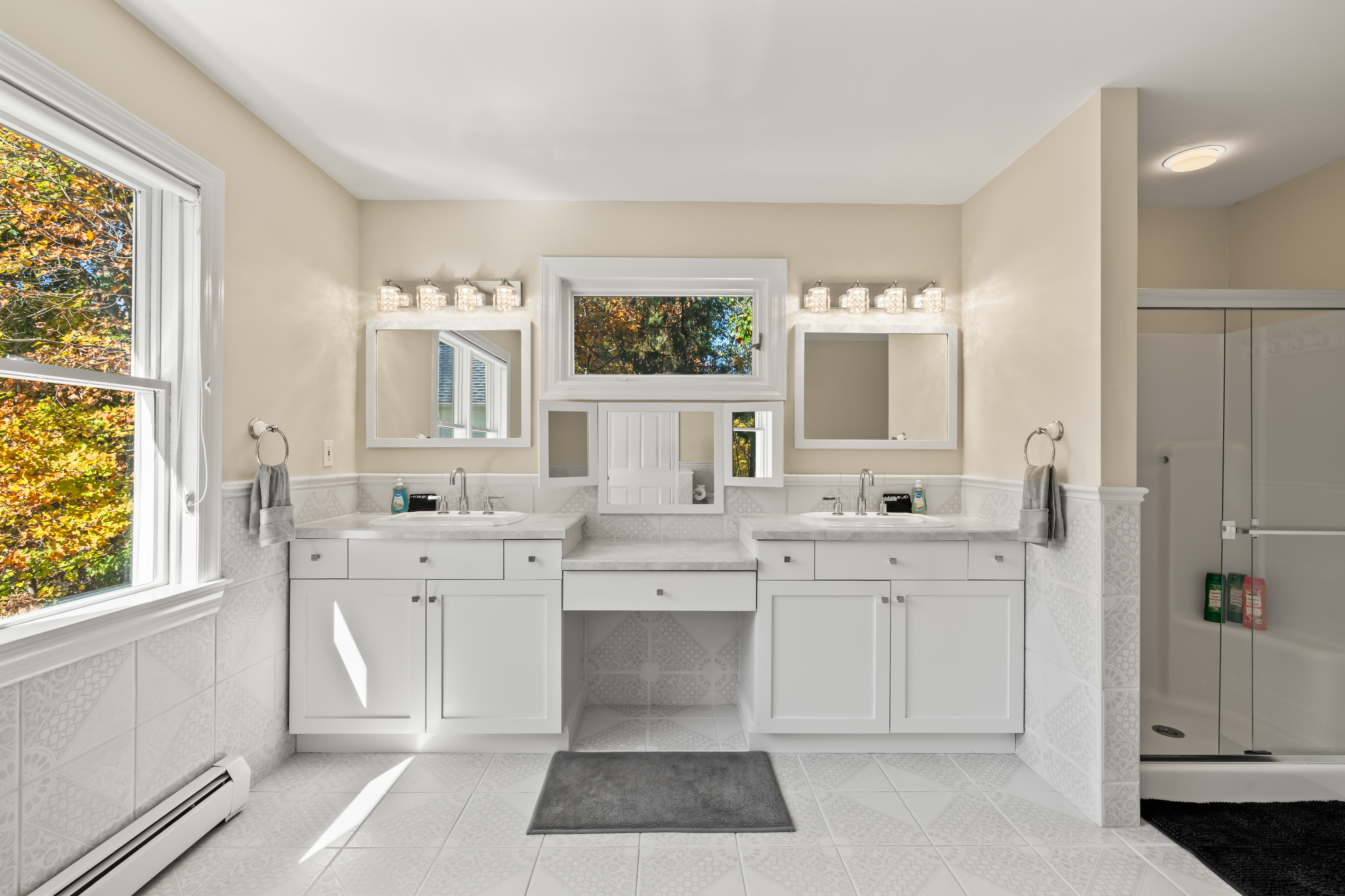 Bright spa-like bathroom with double vanity and glass-enclosed tub/shower