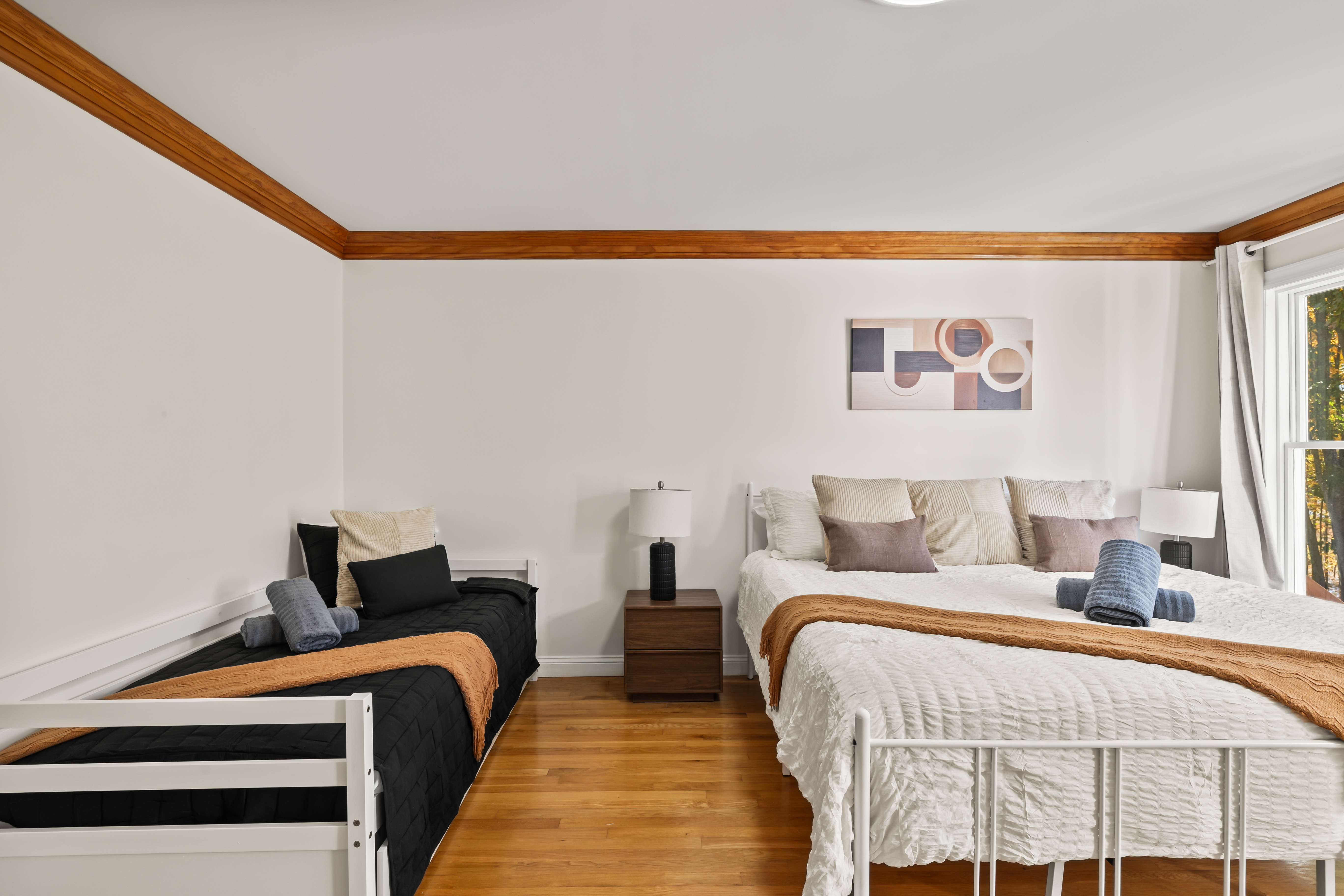 Bright family-friendly bedroom with 2 beds, hardwood floors, and natural light