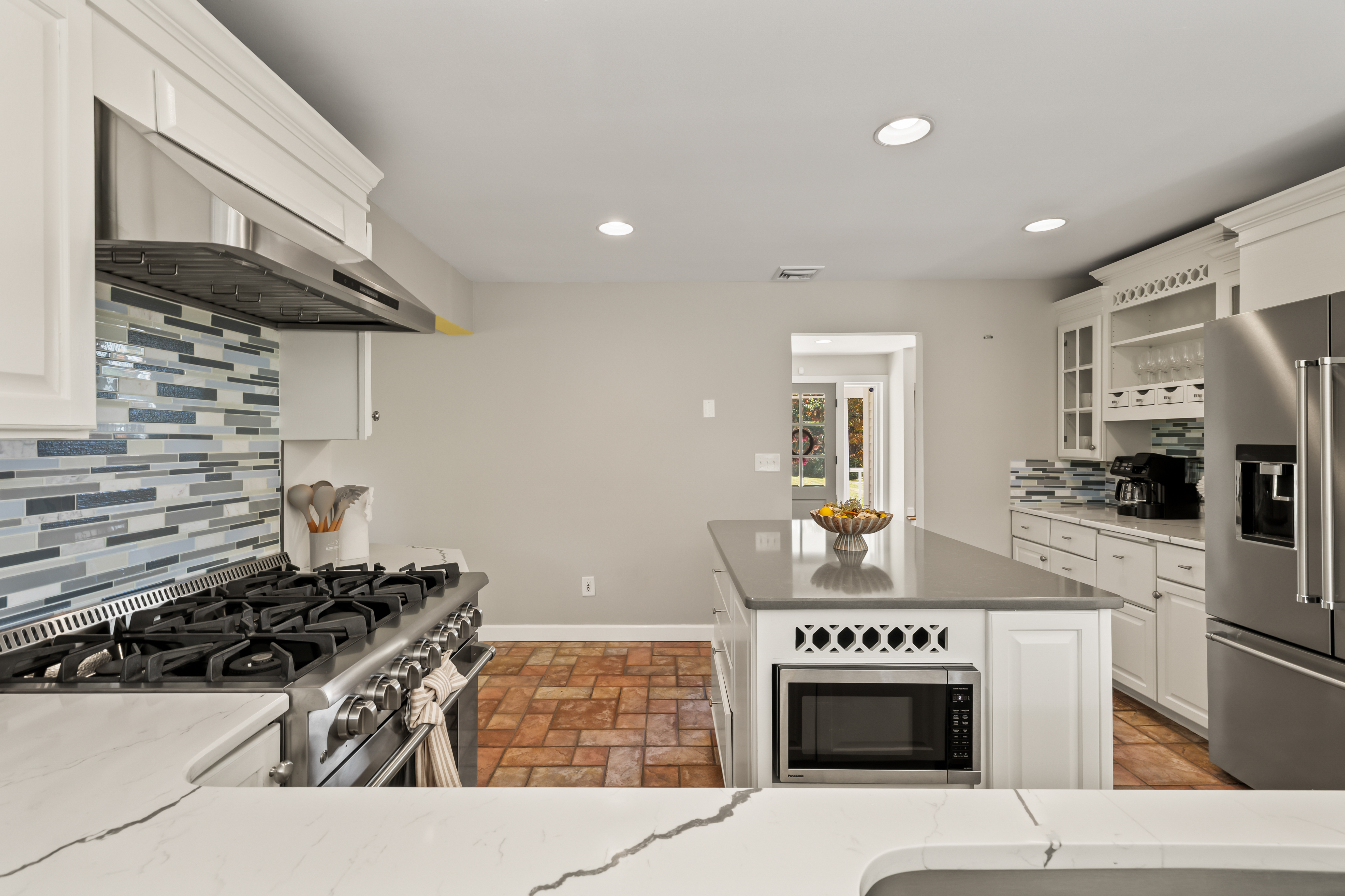 Bright chef’s kitchen with large island, gas range, and modern finishes