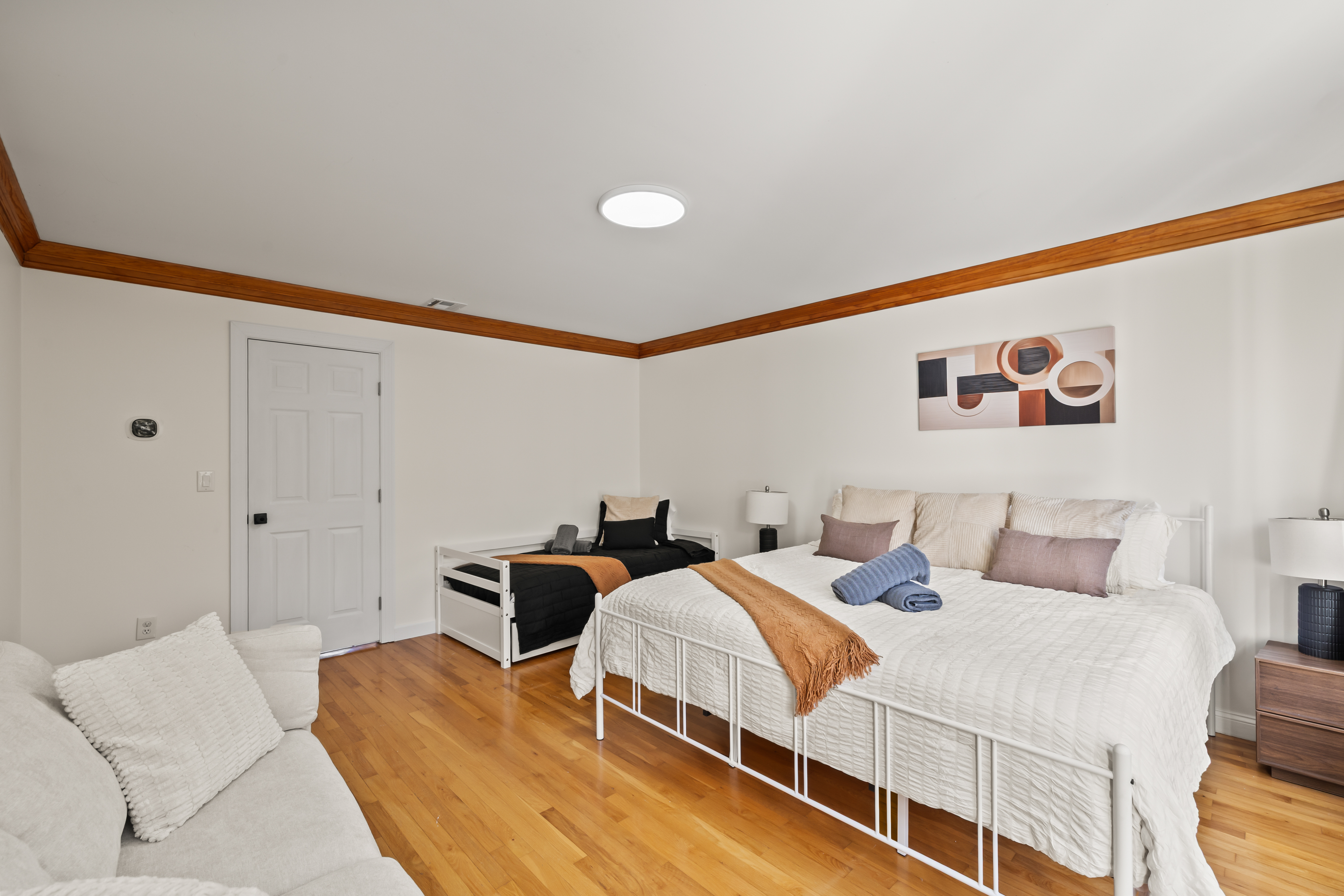 Spacious bright bedroom with king bed, daybed, and warm hardwood floors