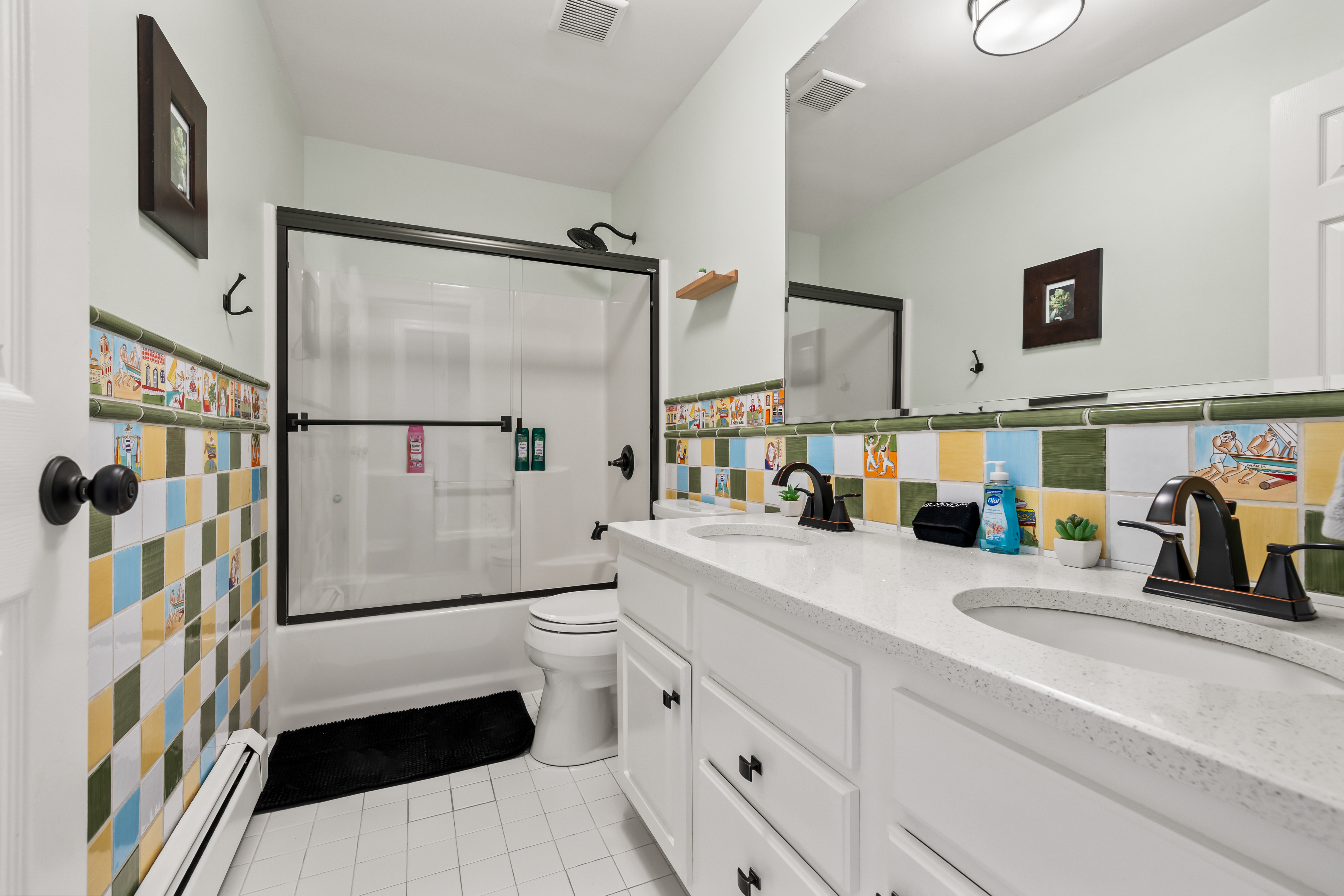 Bright double-vanity bathroom with colorful tile accents and tub/shower