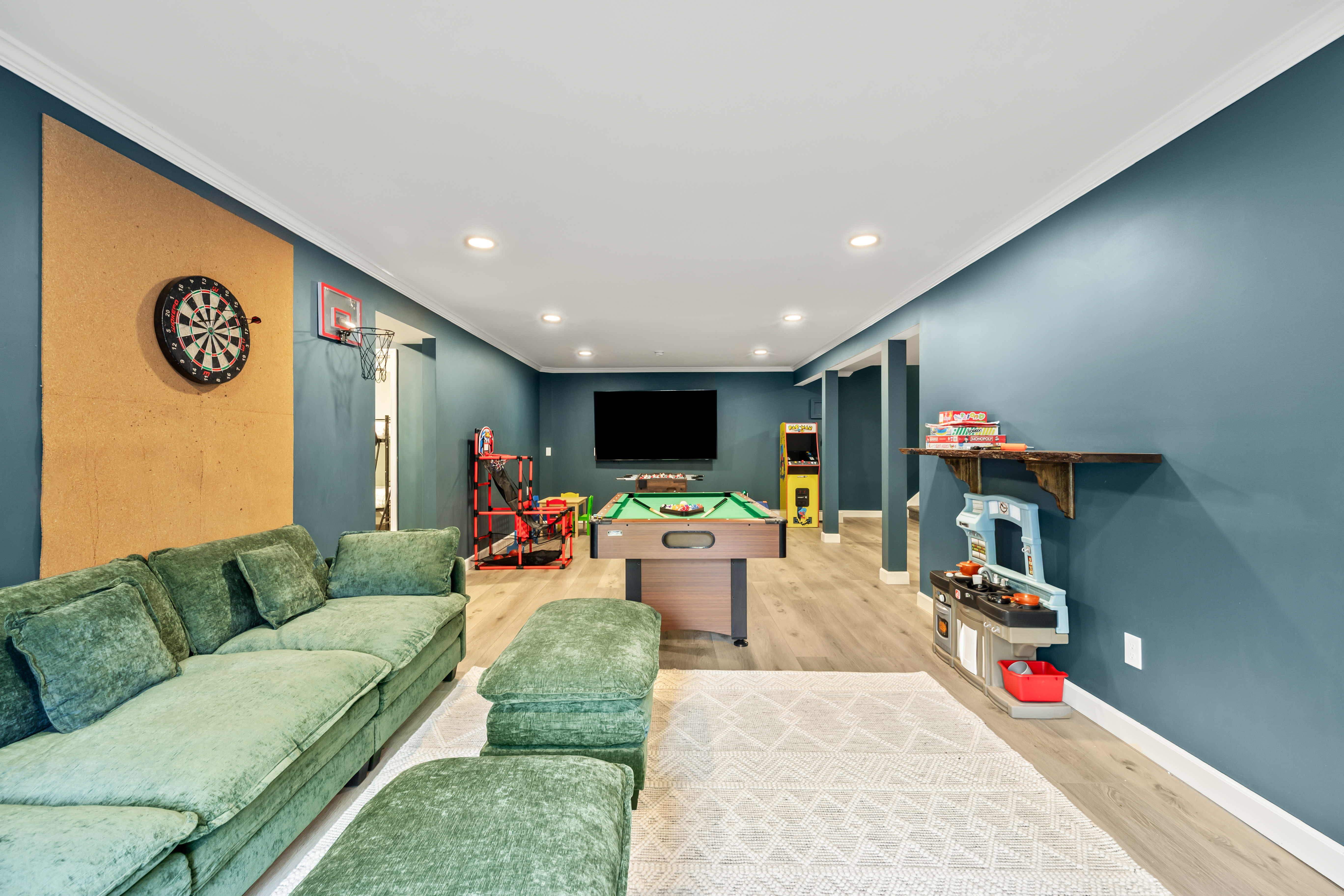 Fun-filled game room with pool table, arcade, darts, and cozy lounge seating