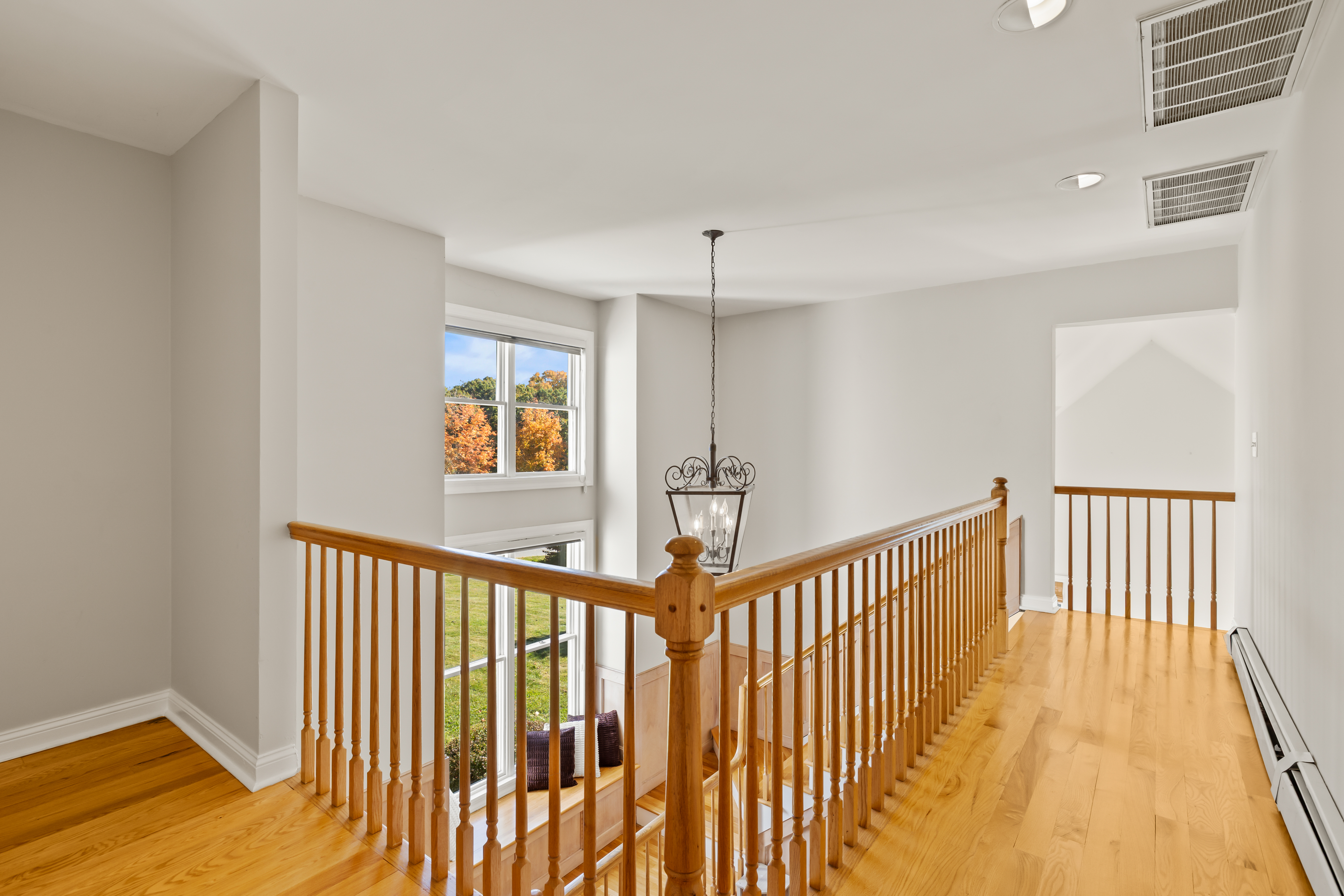 Bright open landing with hardwood floors and sun-filled foyer views