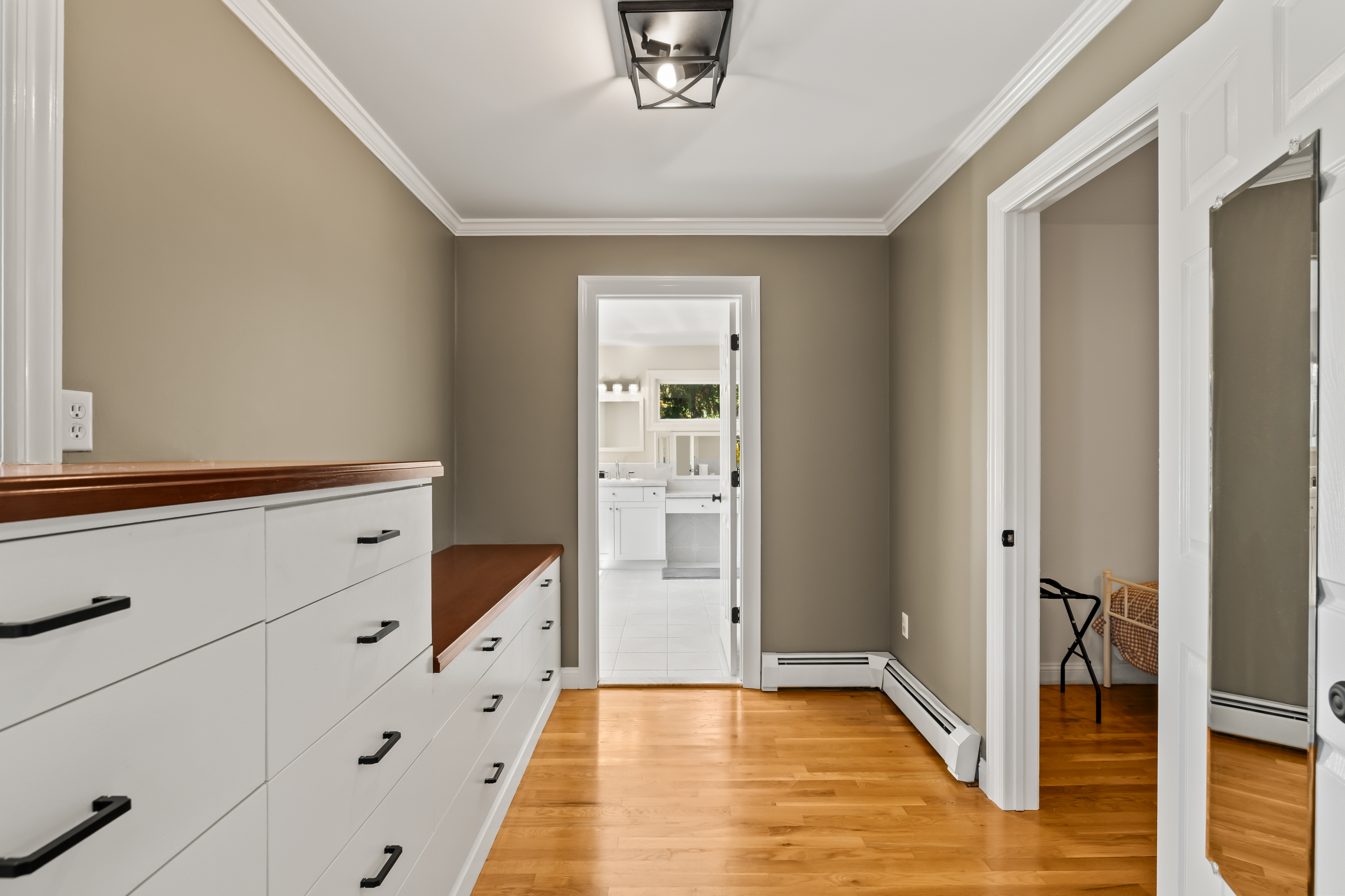 Bright dressing area with built-in storage and hardwood floors