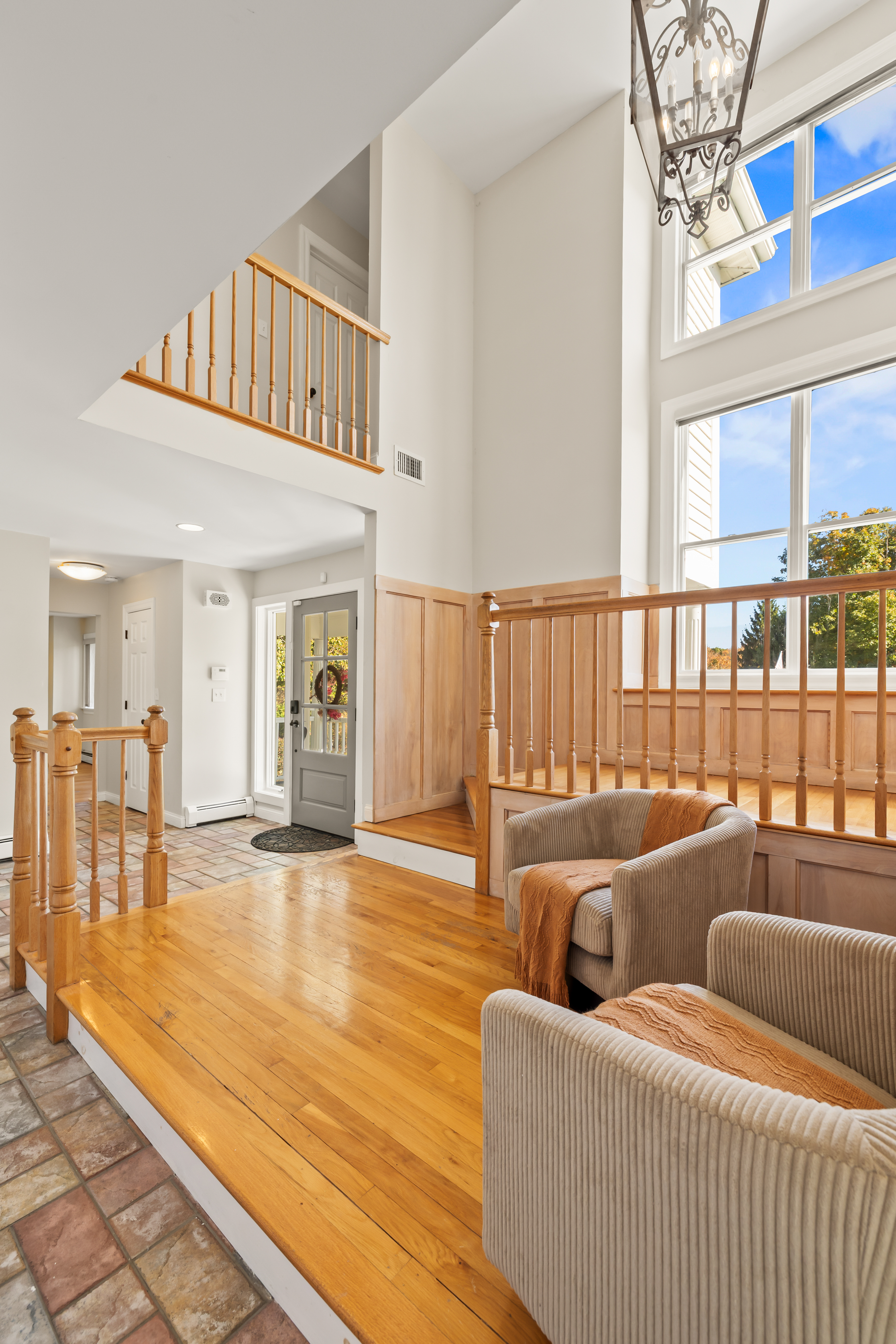 Bright entryway with soaring ceilings, oversized windows, and cozy seating