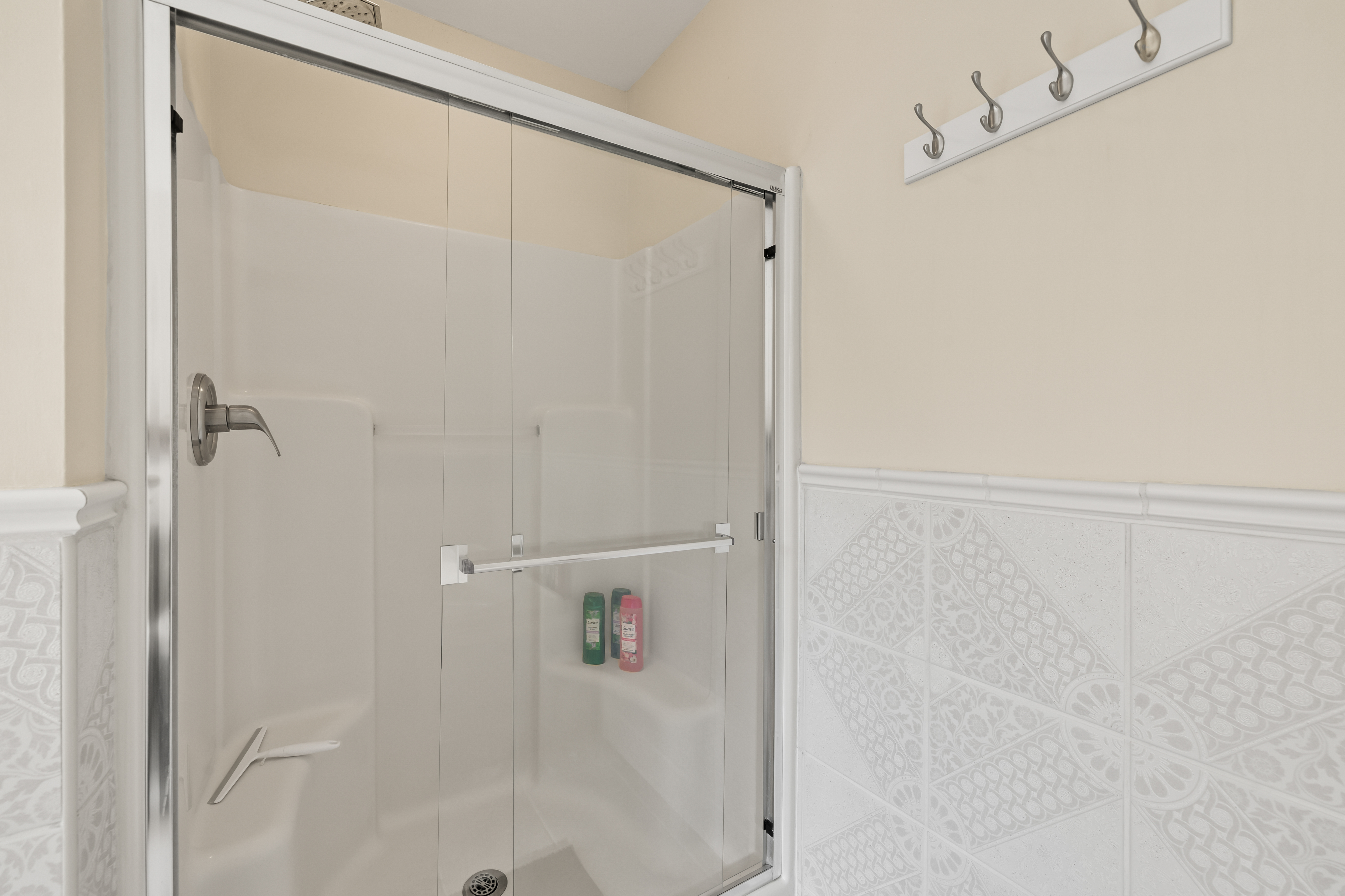 Bright bathroom with glass-door shower and convenient wall hooks