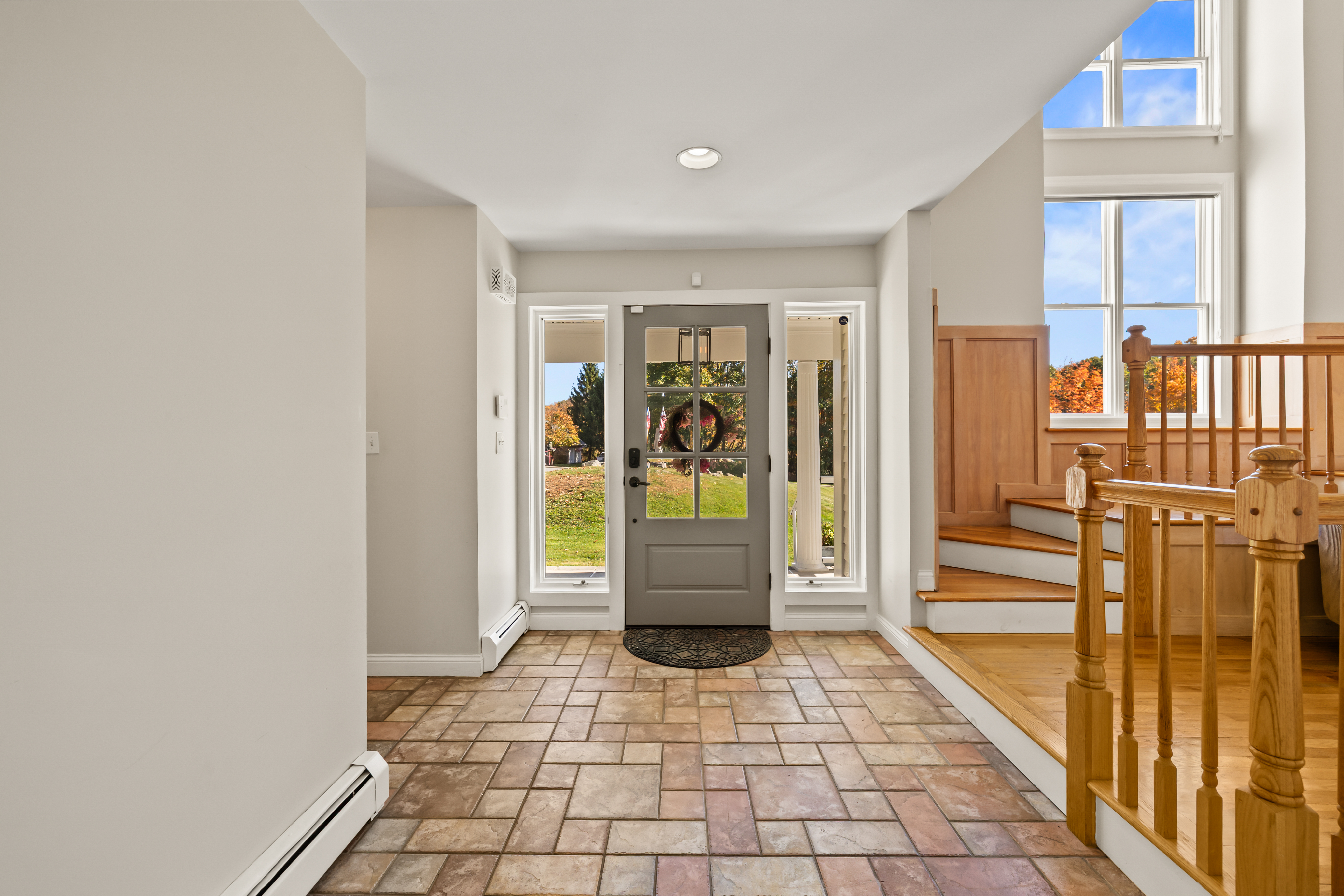 Bright, airy foyer with natural light and a warm wood staircase