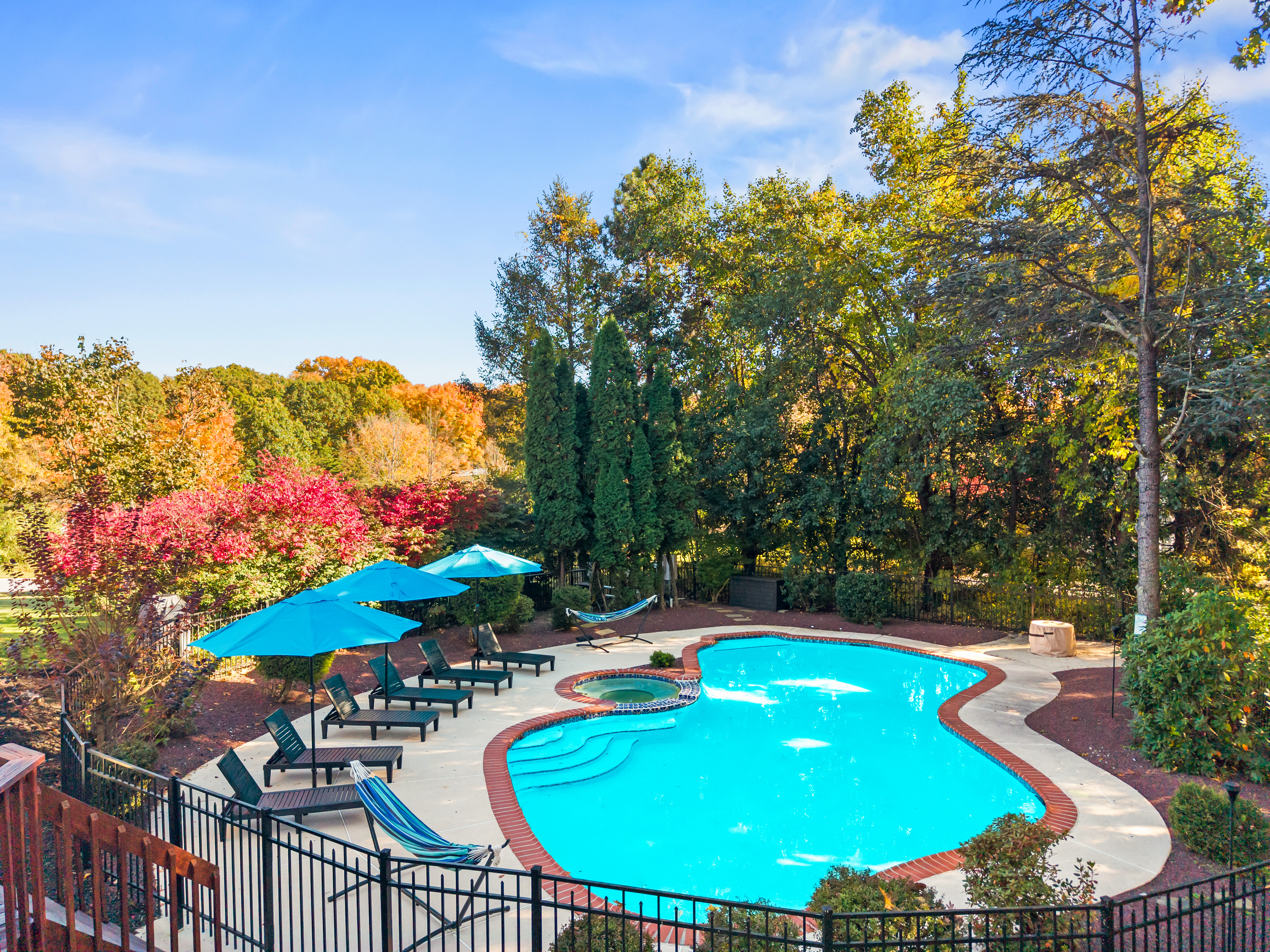 Private pool oasis with spa, loungers, and serene wooded surroundings