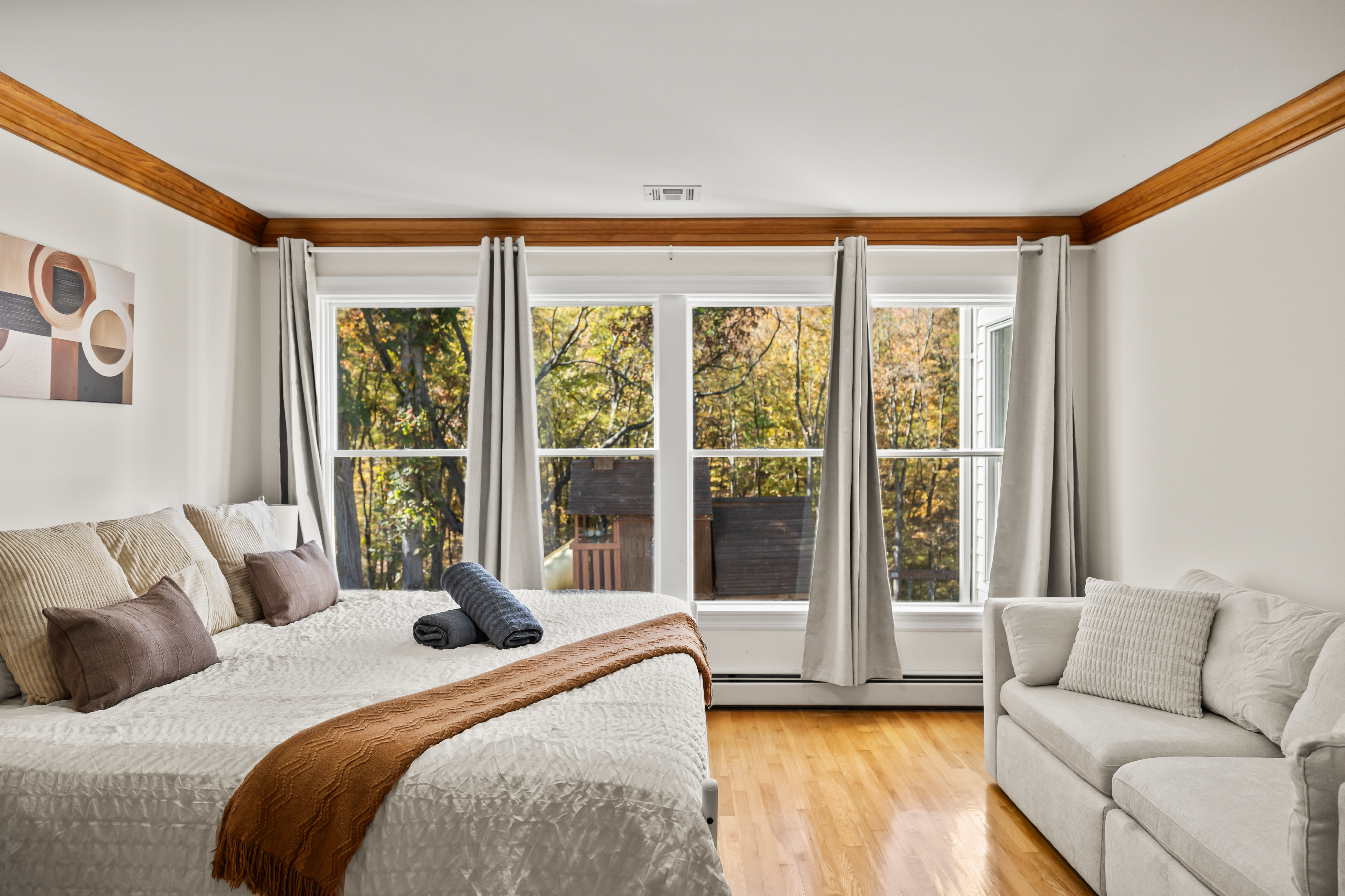 Bright, cozy bedroom with big windows and serene treetop views