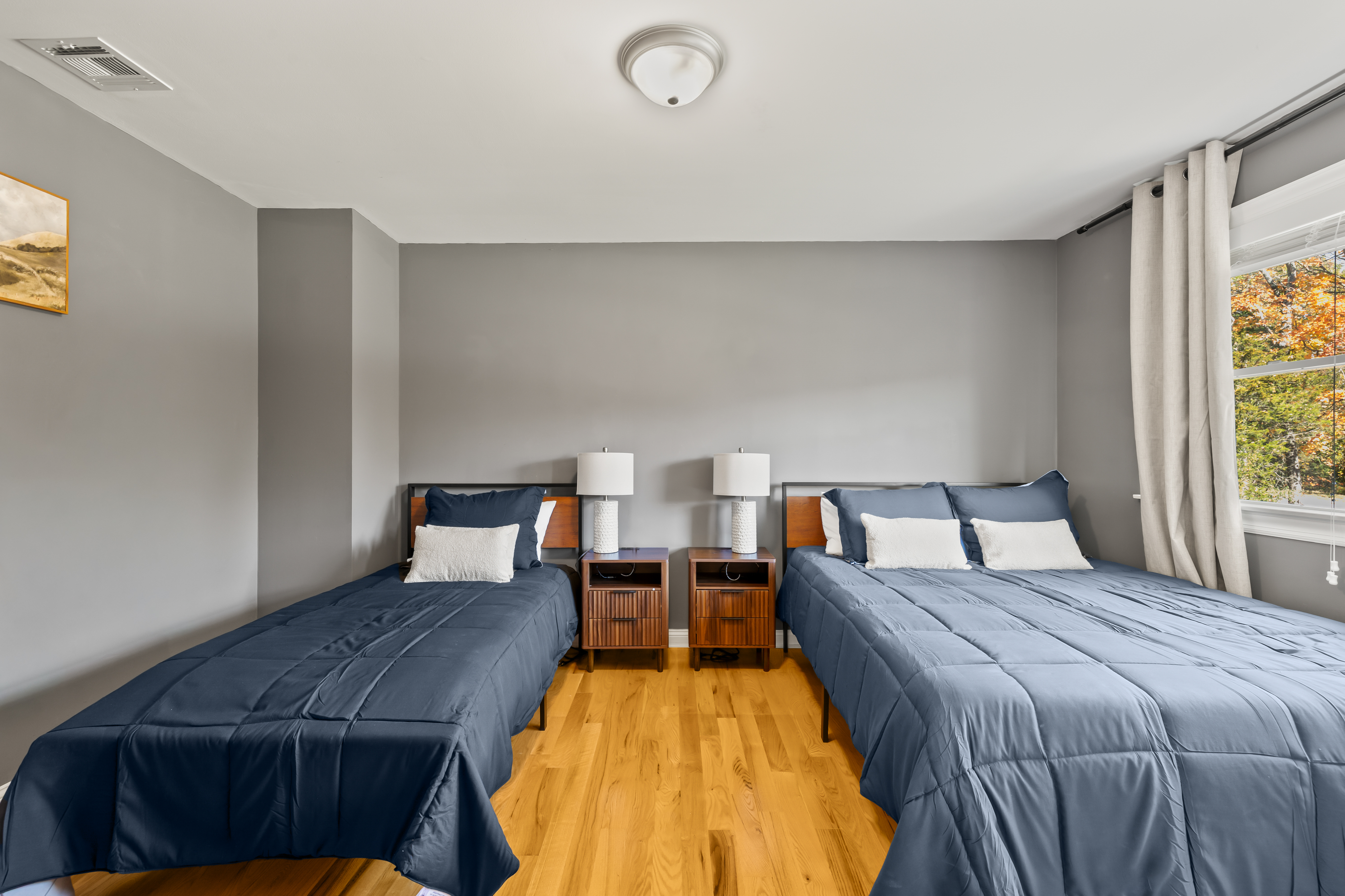 Bright shared bedroom with two beds, hardwood floors, and natural light