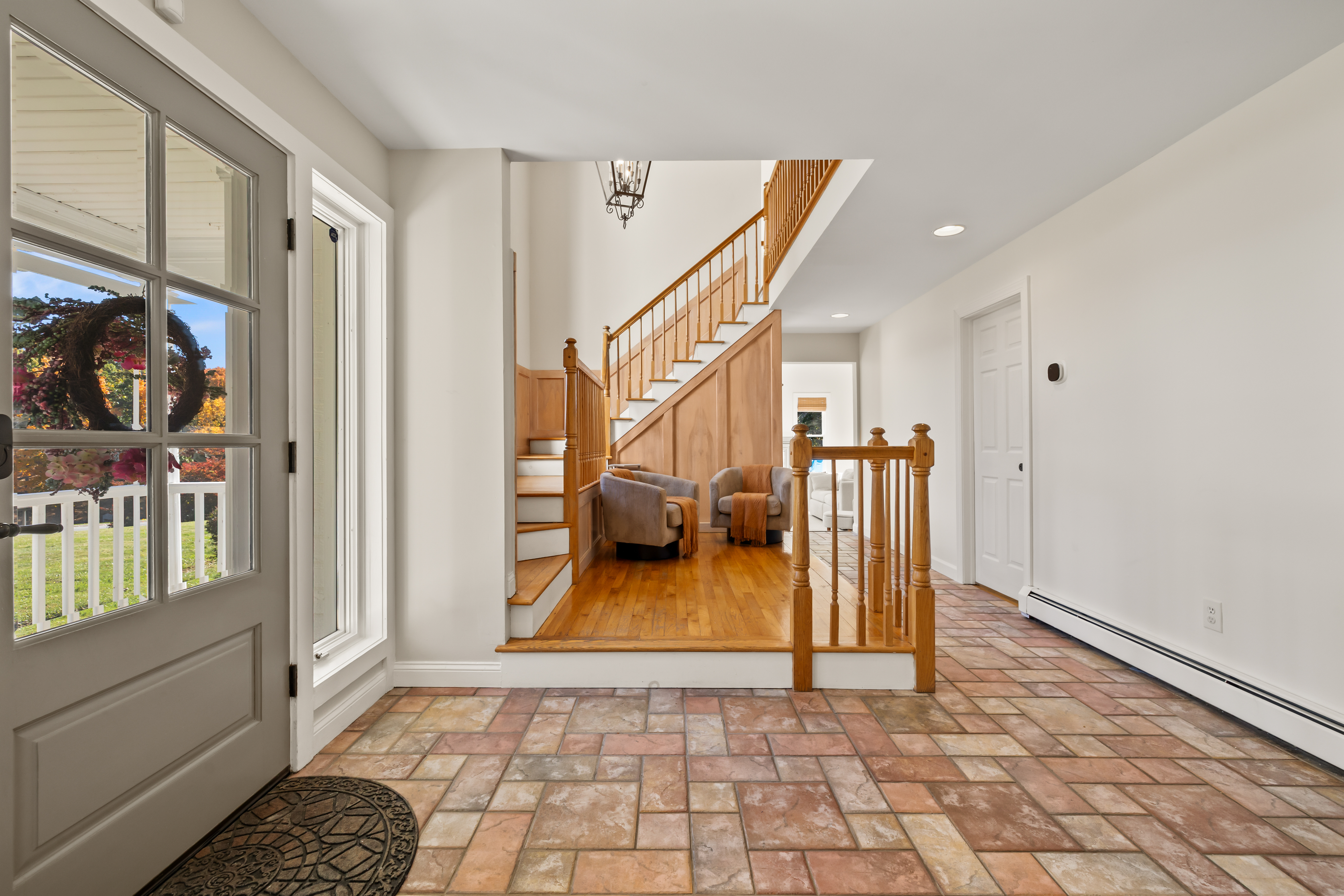 Bright, welcoming entryway with natural light and elegant wood staircase
