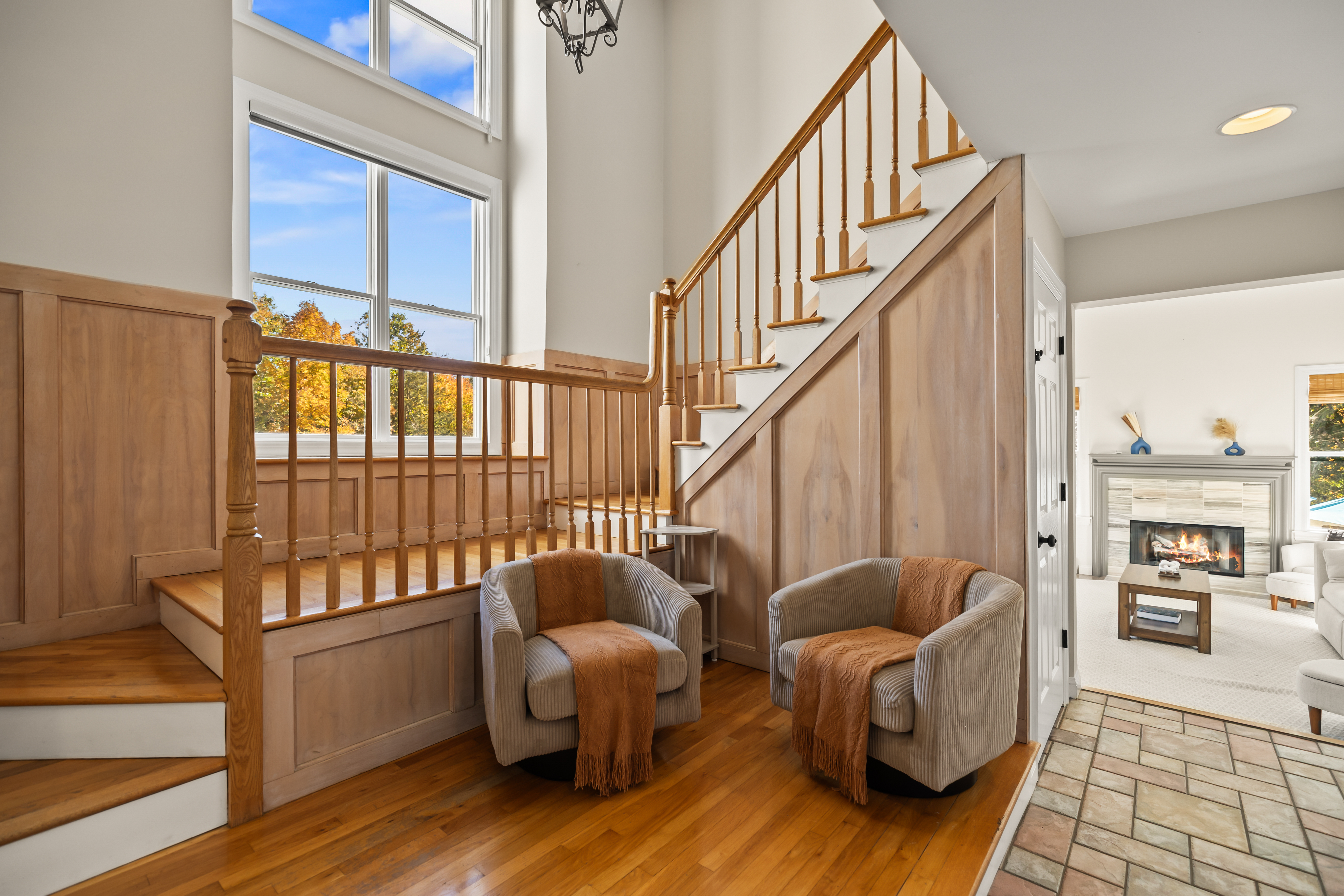 Sunlit entry with soaring ceilings, hardwood floors & cozy fireplace views