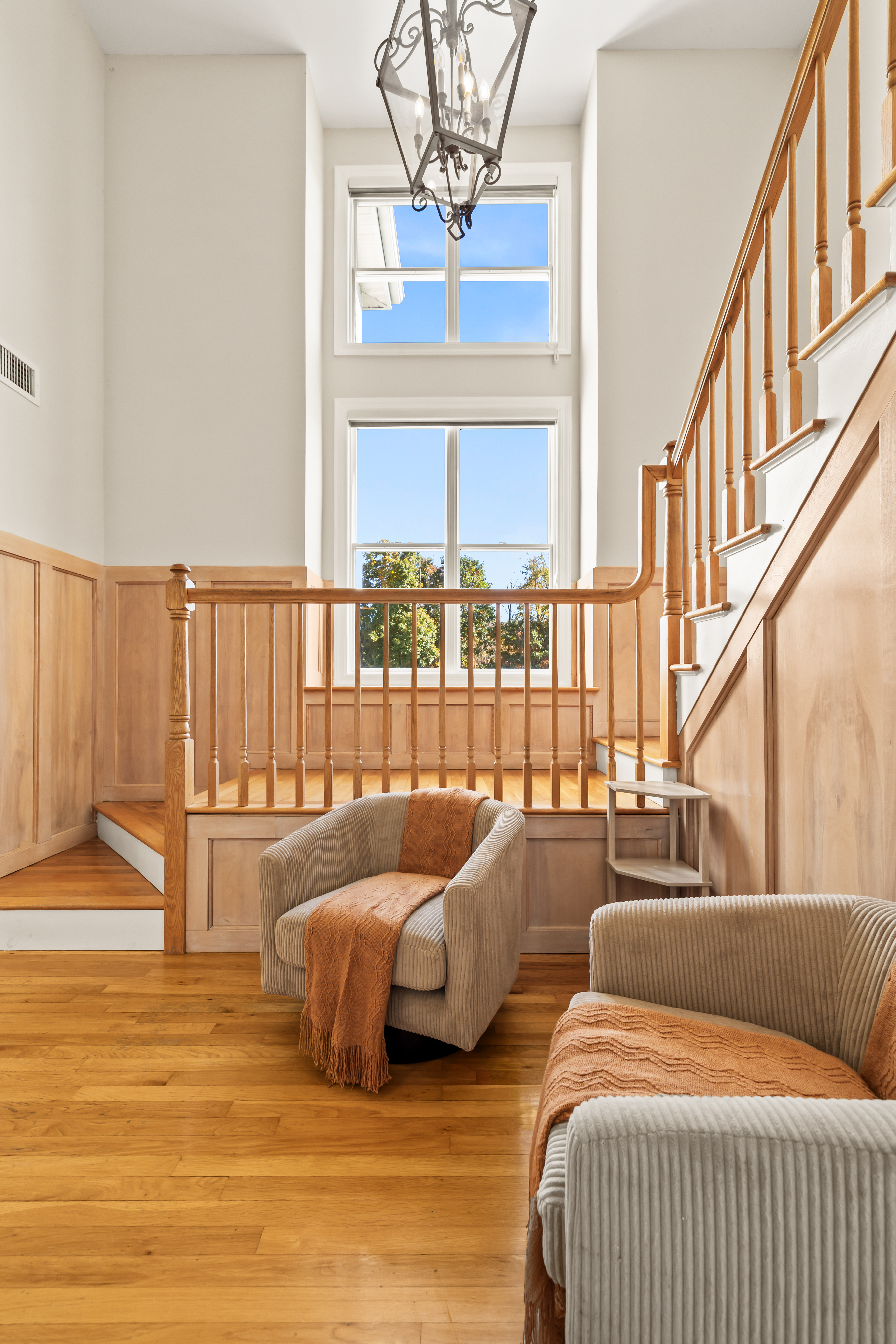 Sun-filled entry with soaring windows, warm woodwork, and cozy seating