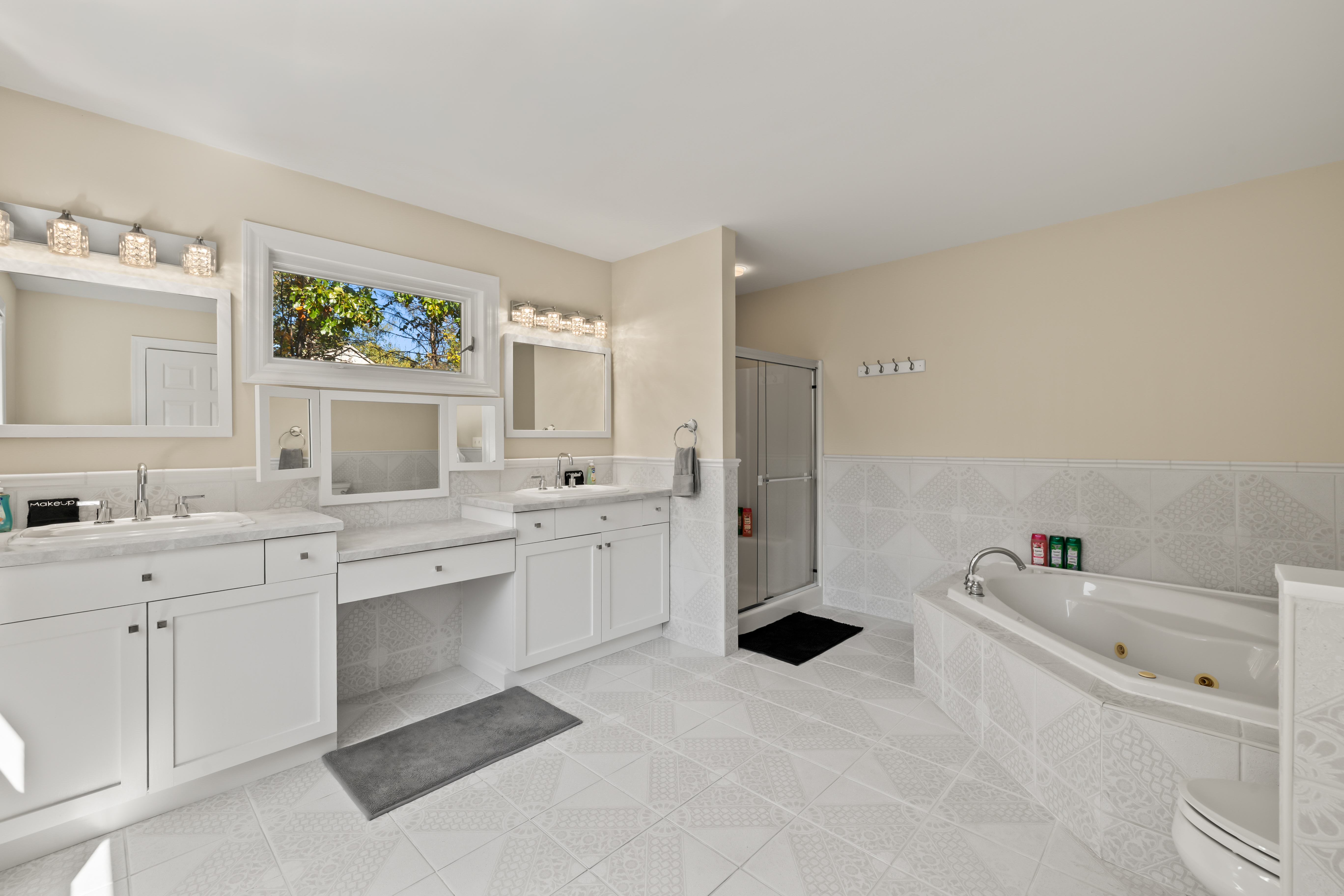 Bright spa-like bathroom with soaking tub, dual vanities, and walk-in shower
