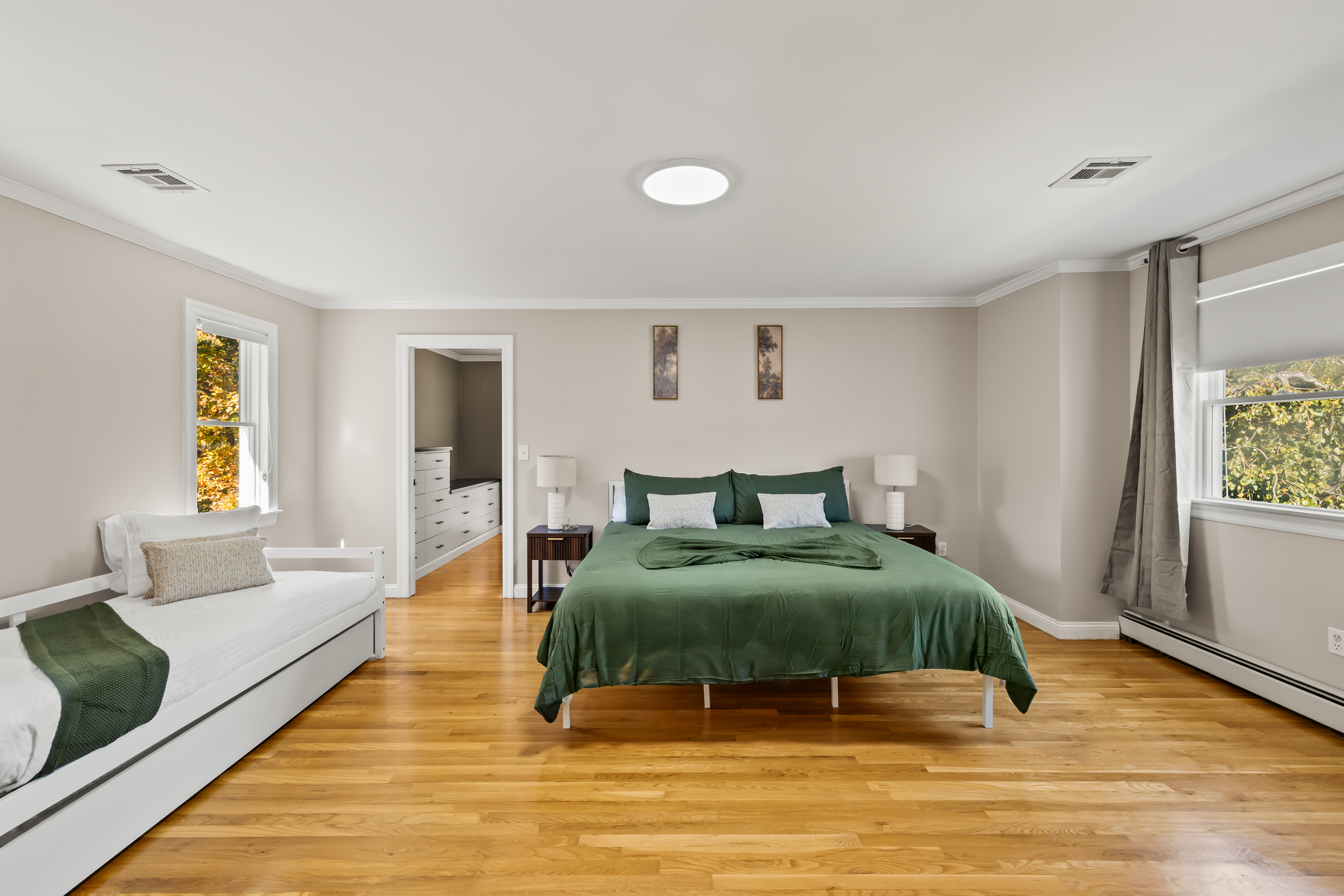 Spacious sunlit bedroom with king bed, daybed, and warm hardwood floors