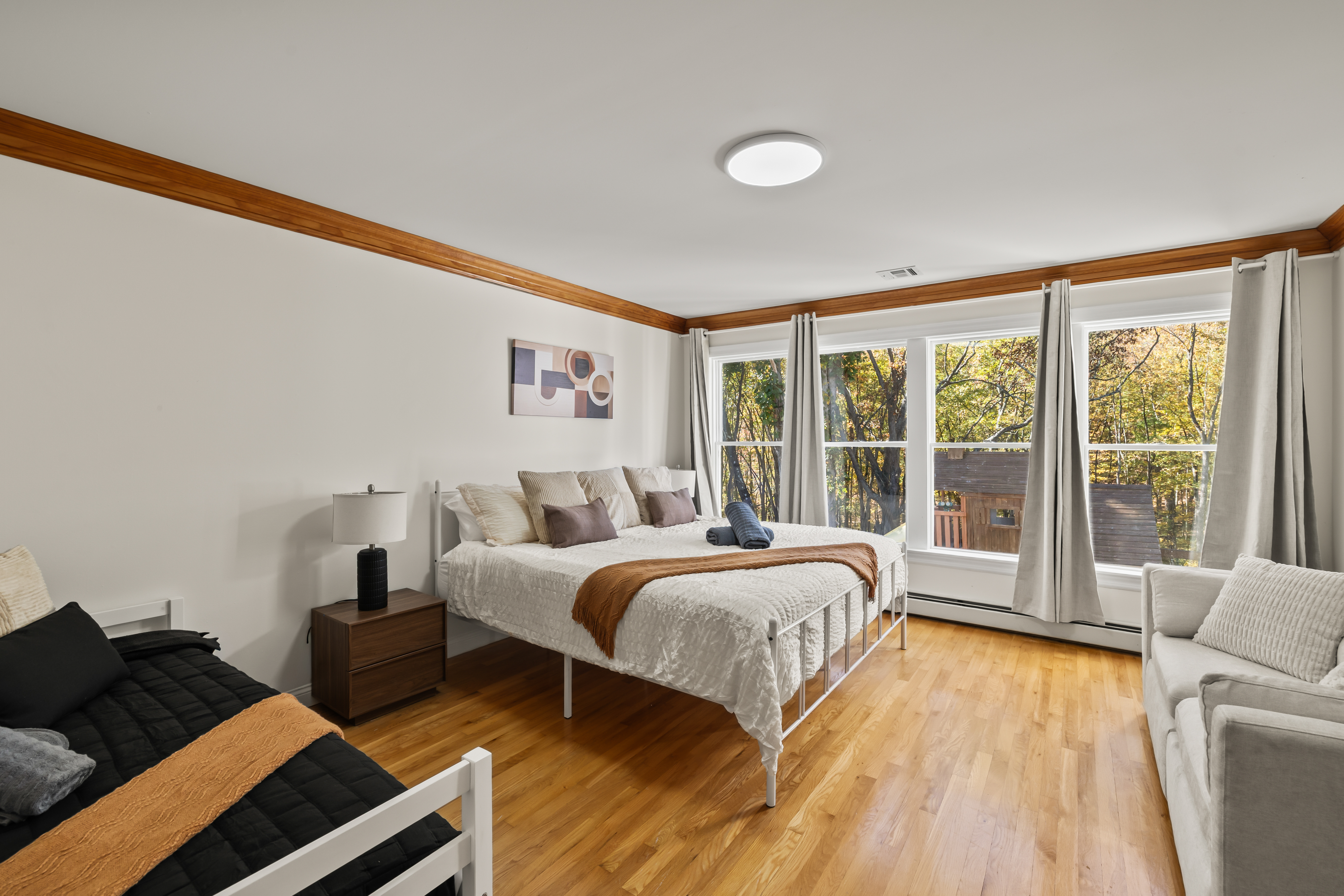 Bright, spacious bedroom with wooded views and cozy seating