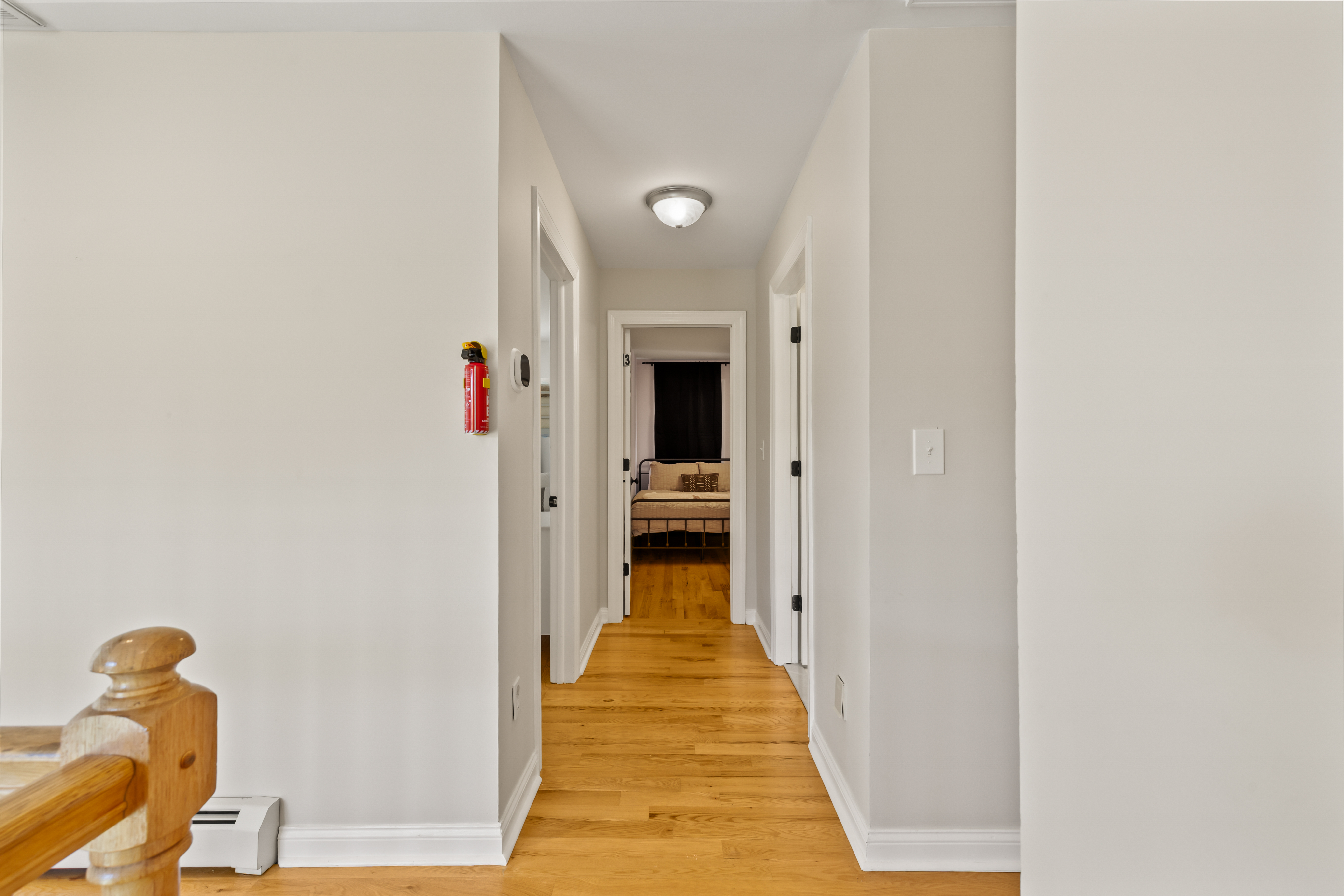 Bright hallway with hardwood floors leading to a cozy bedroom retreat