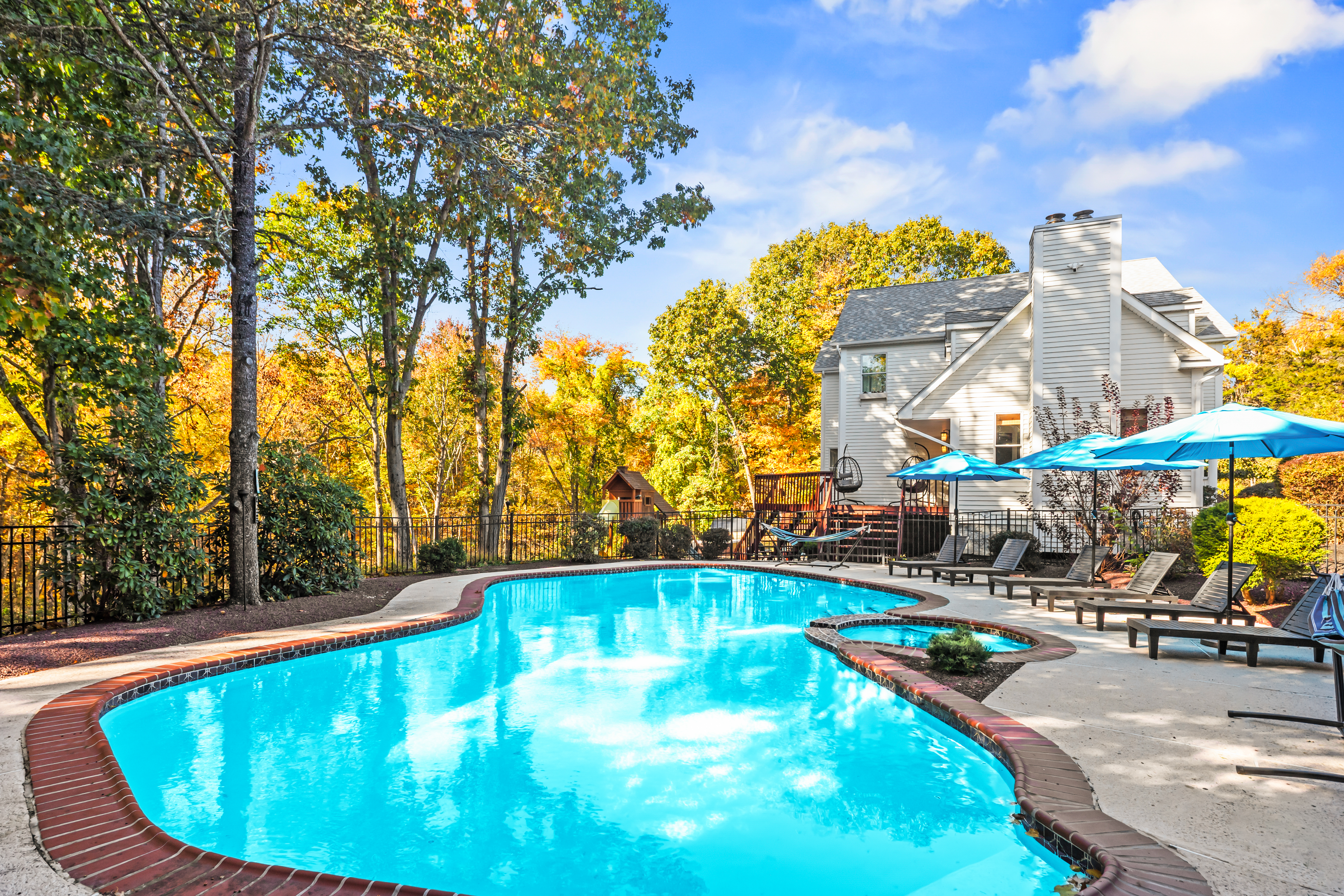 Private resort-style pool with spa, loungers, and a serene wooded backdrop