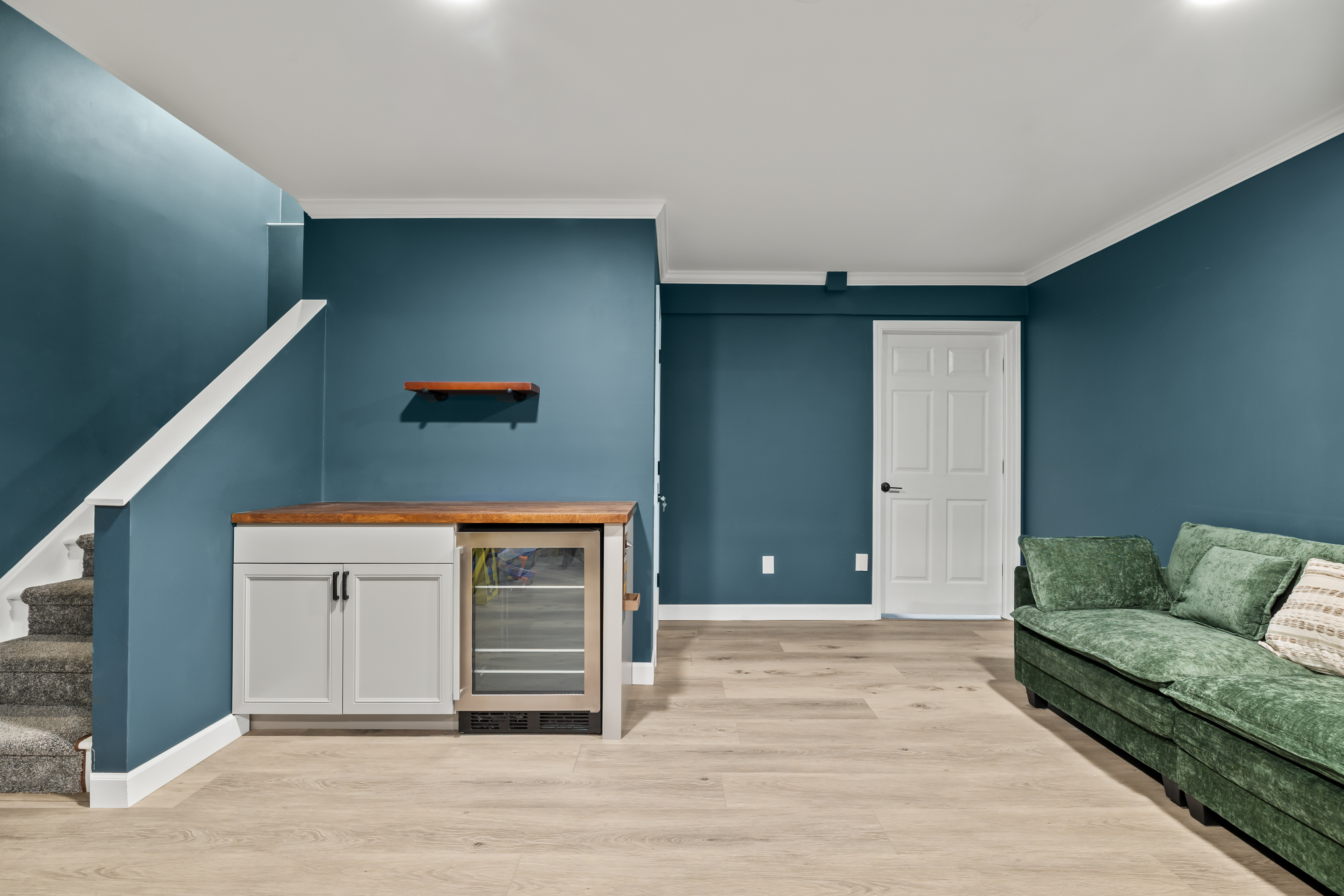 Stylish lower-level lounge with mini fridge, cozy seating, and modern finishes