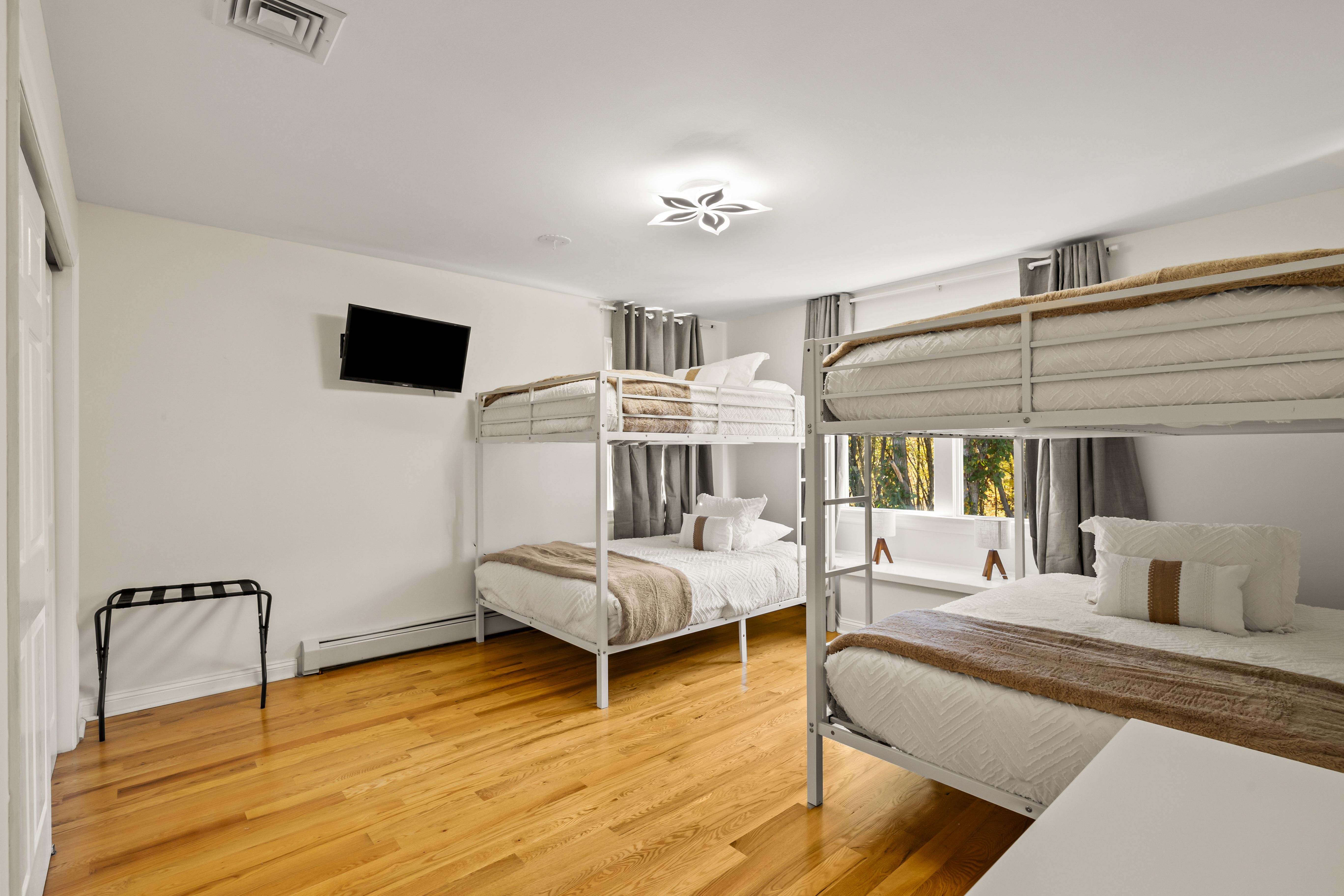 Bright bunk room with hardwood floors, TV, and space for groups