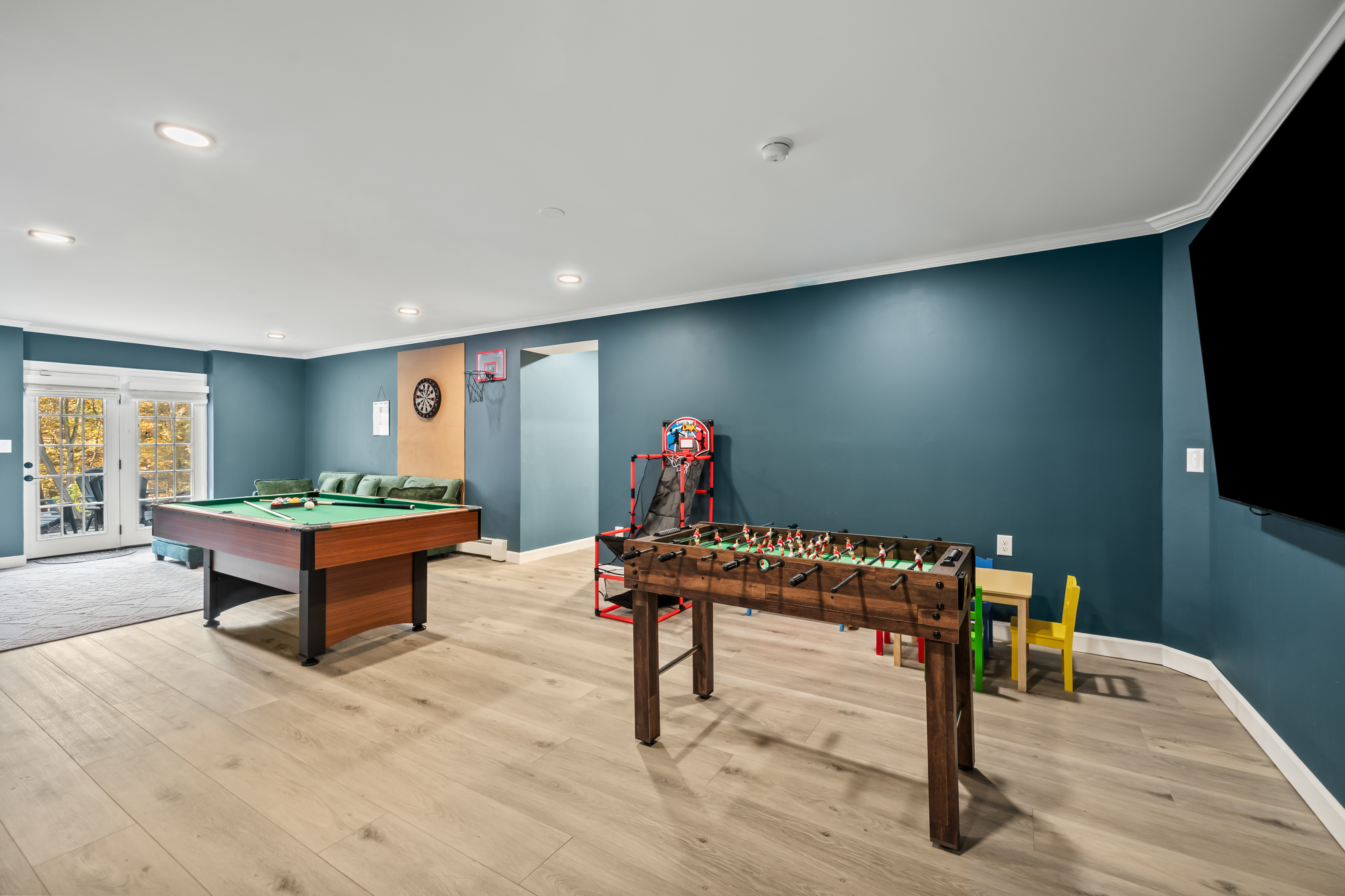 Spacious game room with pool, foosball, arcade hoops, and big-screen TV