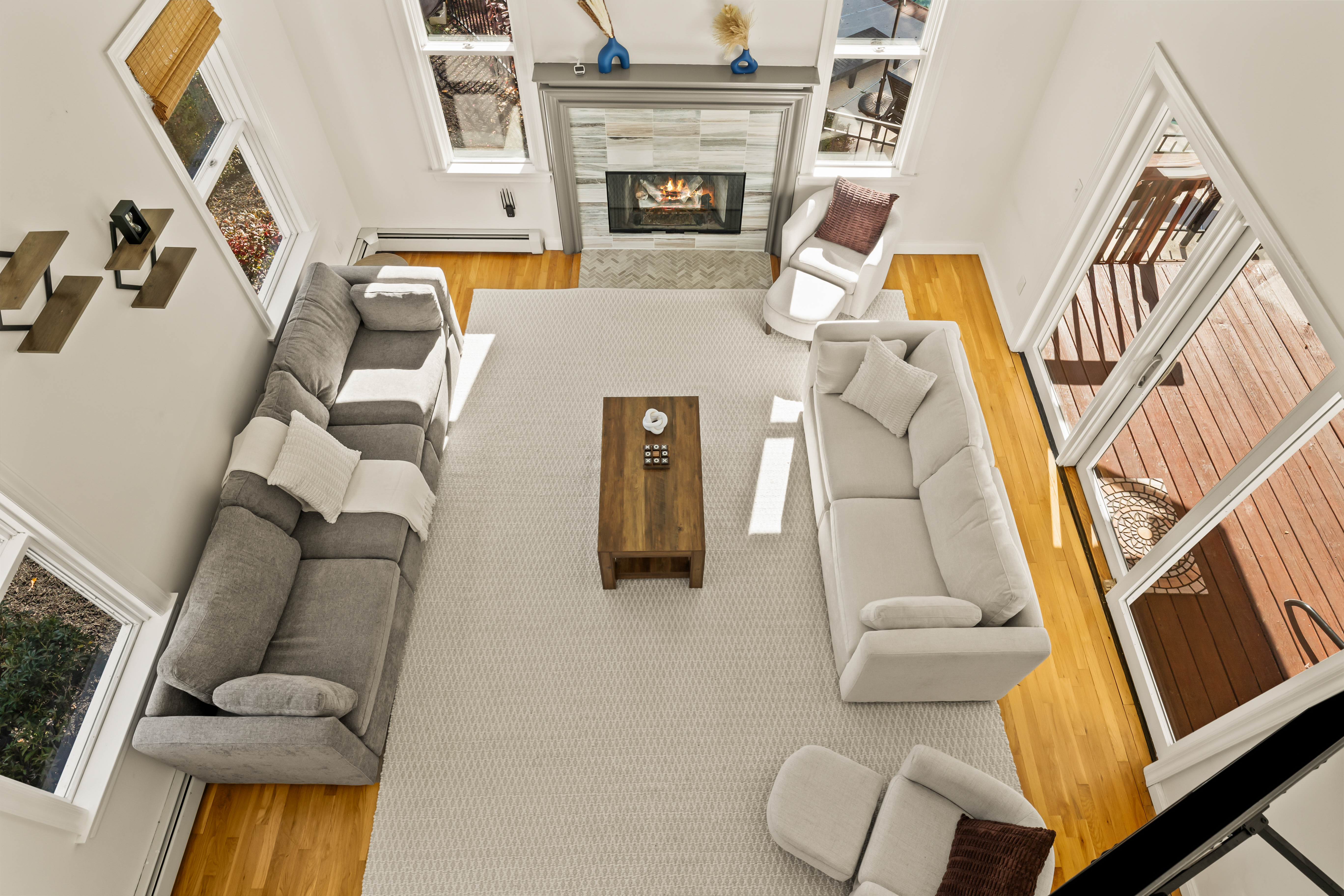 Sun-filled living room with fireplace, vaulted ceilings, and deck access