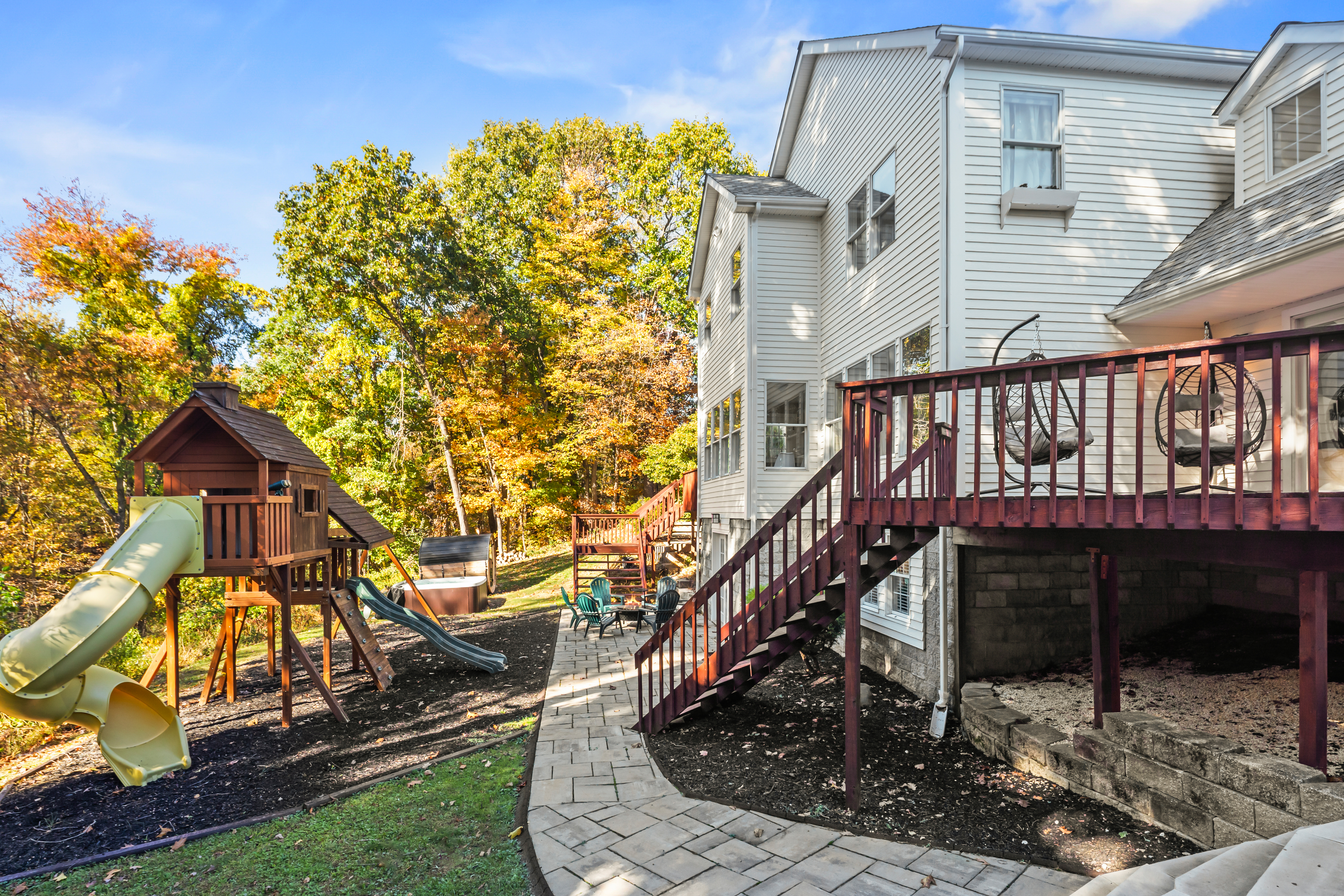 Private backyard with deck, patio seating, and family-friendly playset