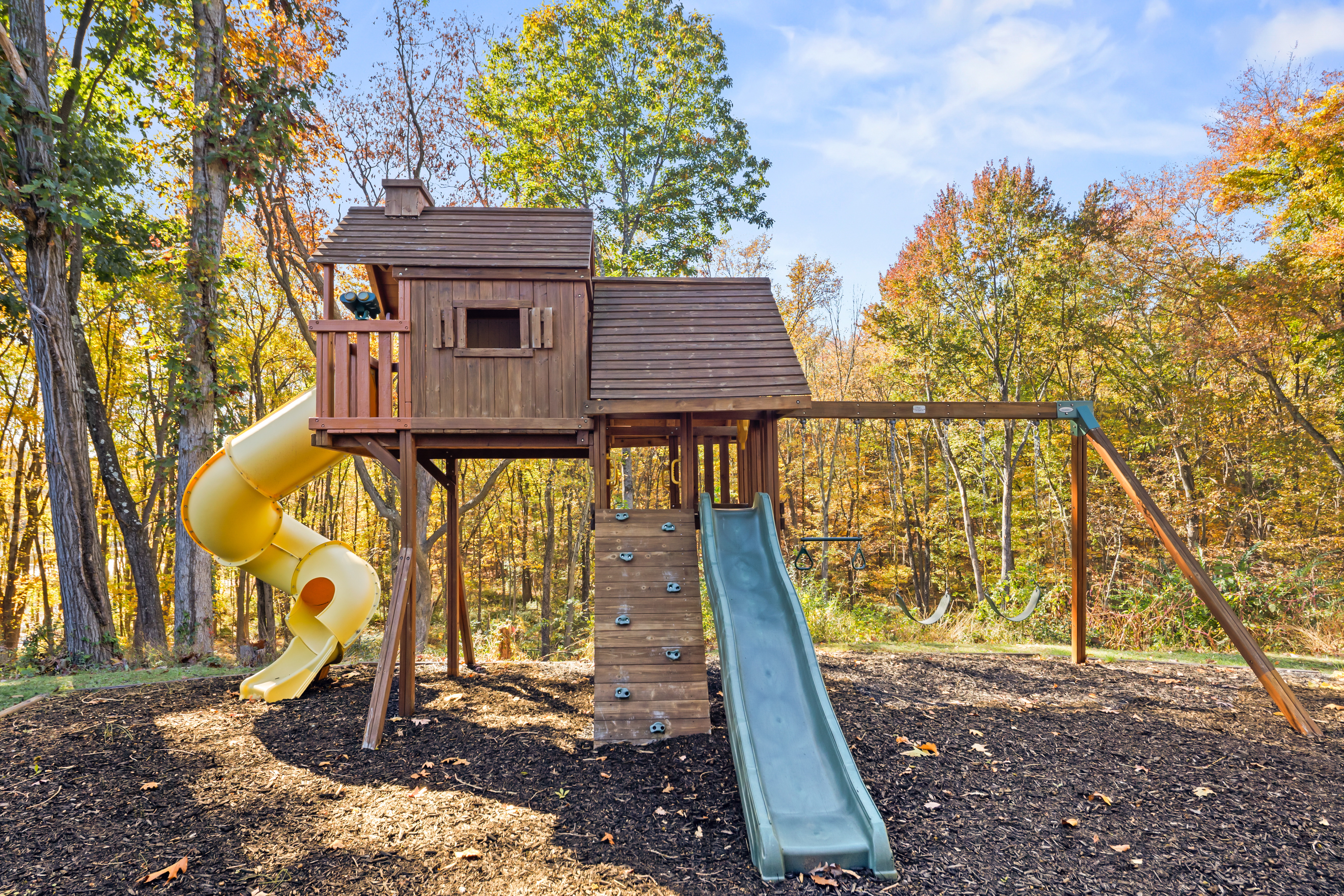 Private wooded playground with slides, swings, and a charming treehouse
