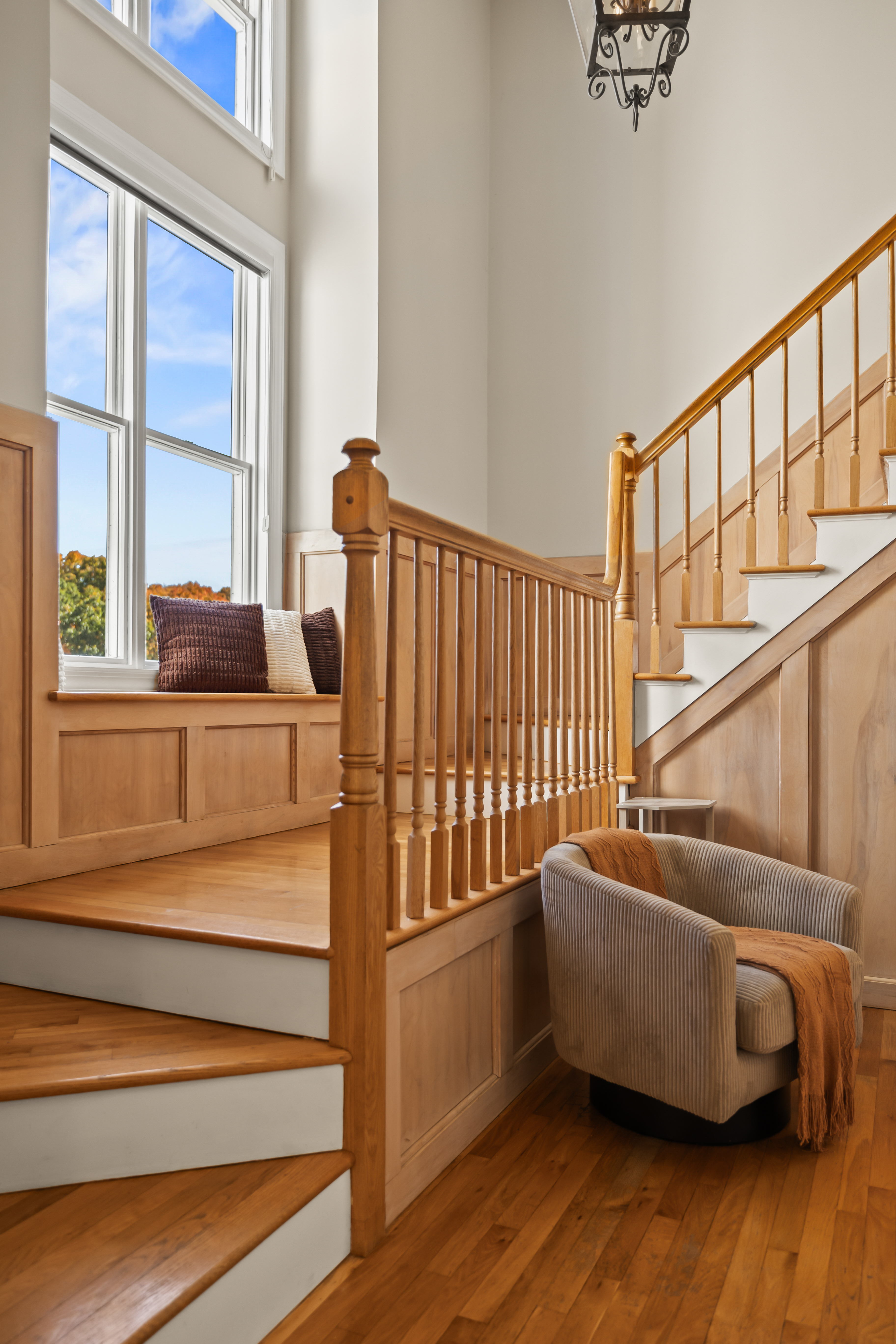 Sunlit grand staircase with soaring ceilings and a cozy window seat