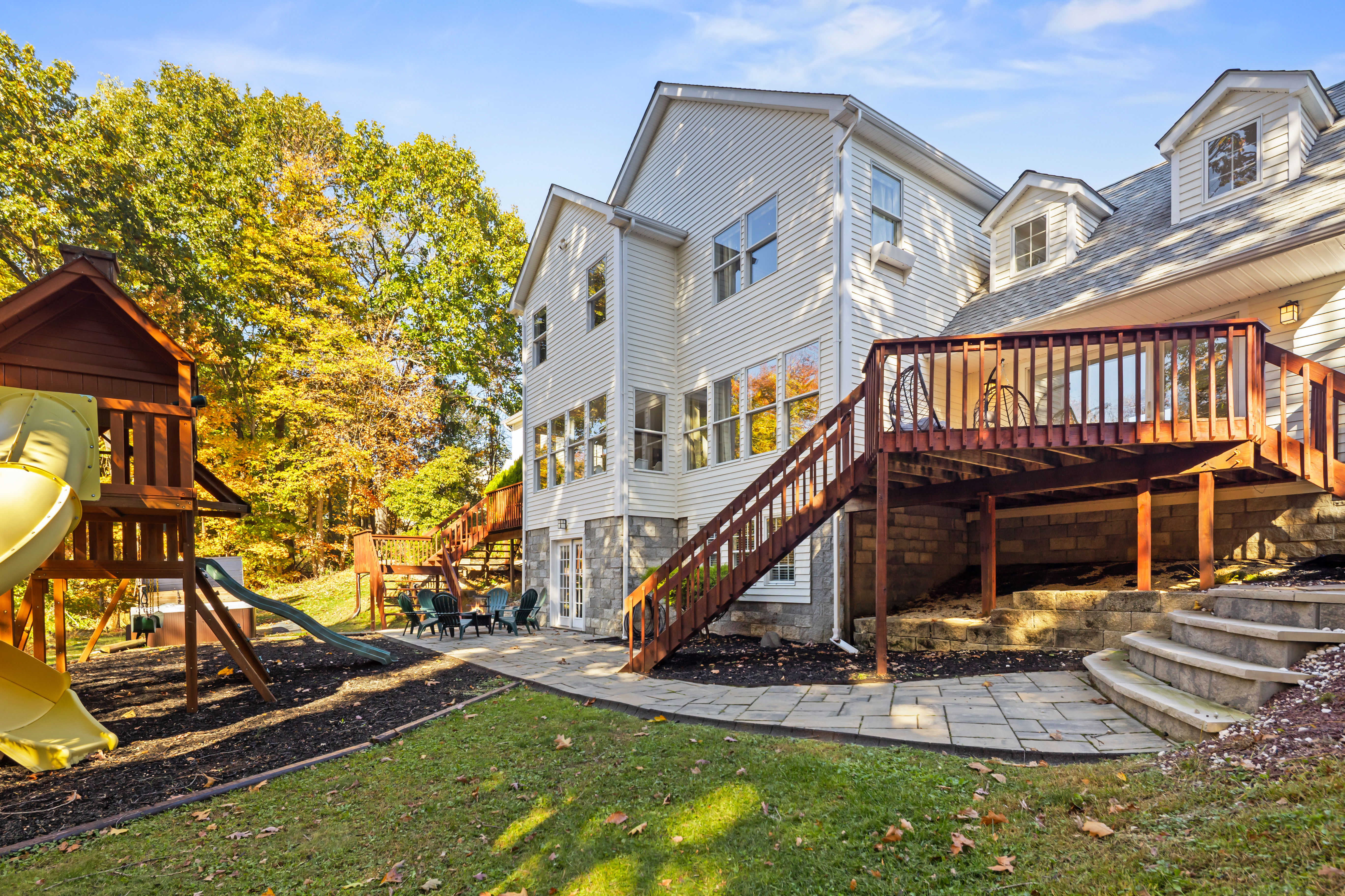 Spacious backyard with deck, patio seating, and a fun private playground